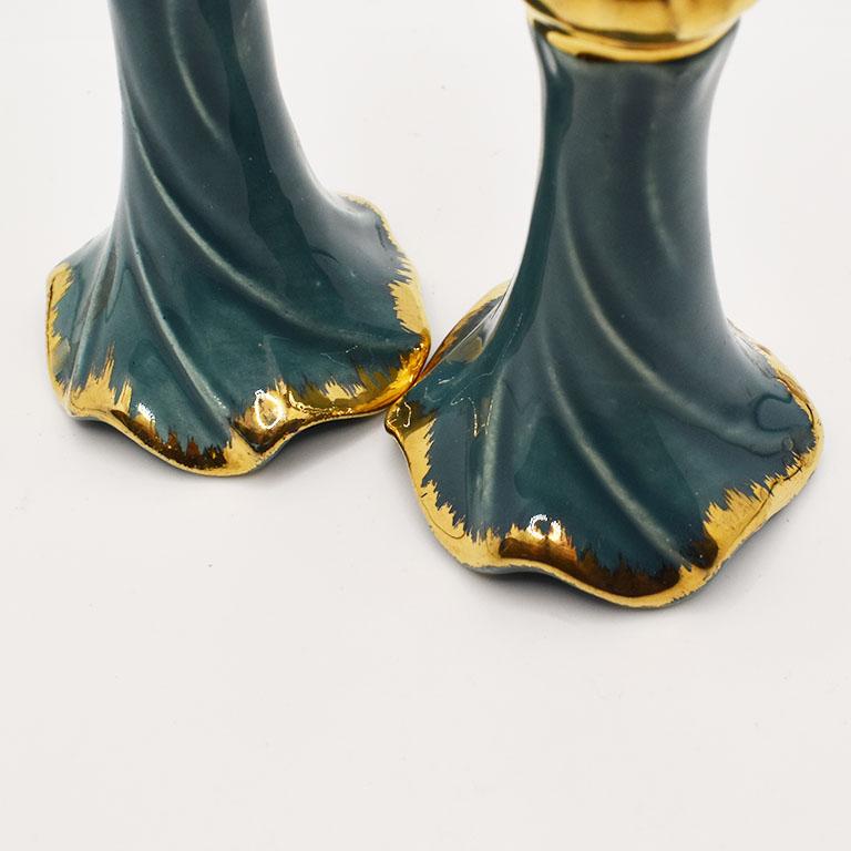 A stunning pair of ceramic Hollywood Regency style candlesticks. Each piece is shaped in a faux ruffle style, giving the look of a ruffled piece of fabric. The middle is glazed in a deep turquoise hue, with gold accents at the top and bottom.