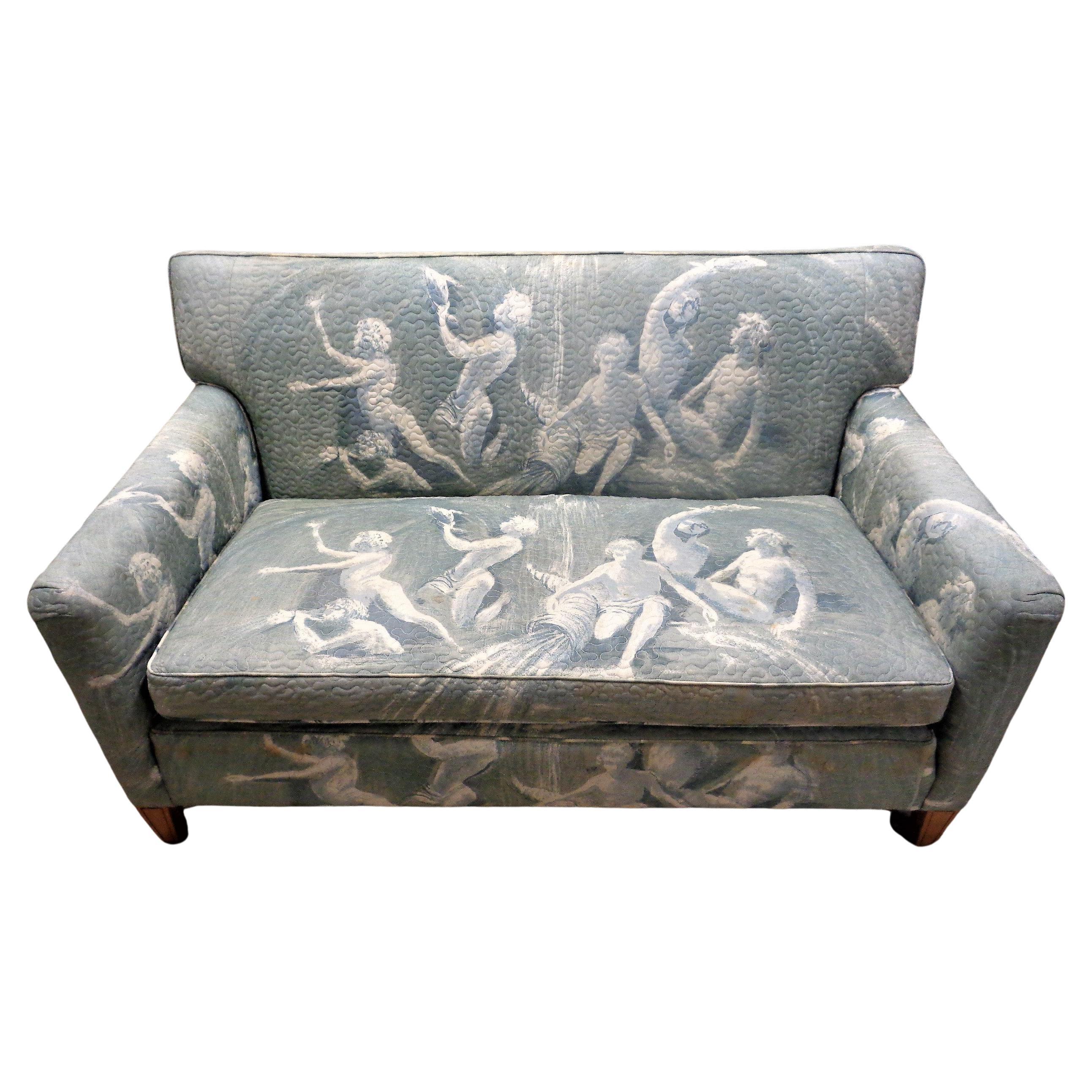  Hollywood Regency tuxedo form loveseat w/ an exotic vintage stitched quilted design cotton upholstery in overall decoration showing mythological faun figures, fish, shell in scenic seascape. Circa 1940-1960. Look at all pictures and read condition