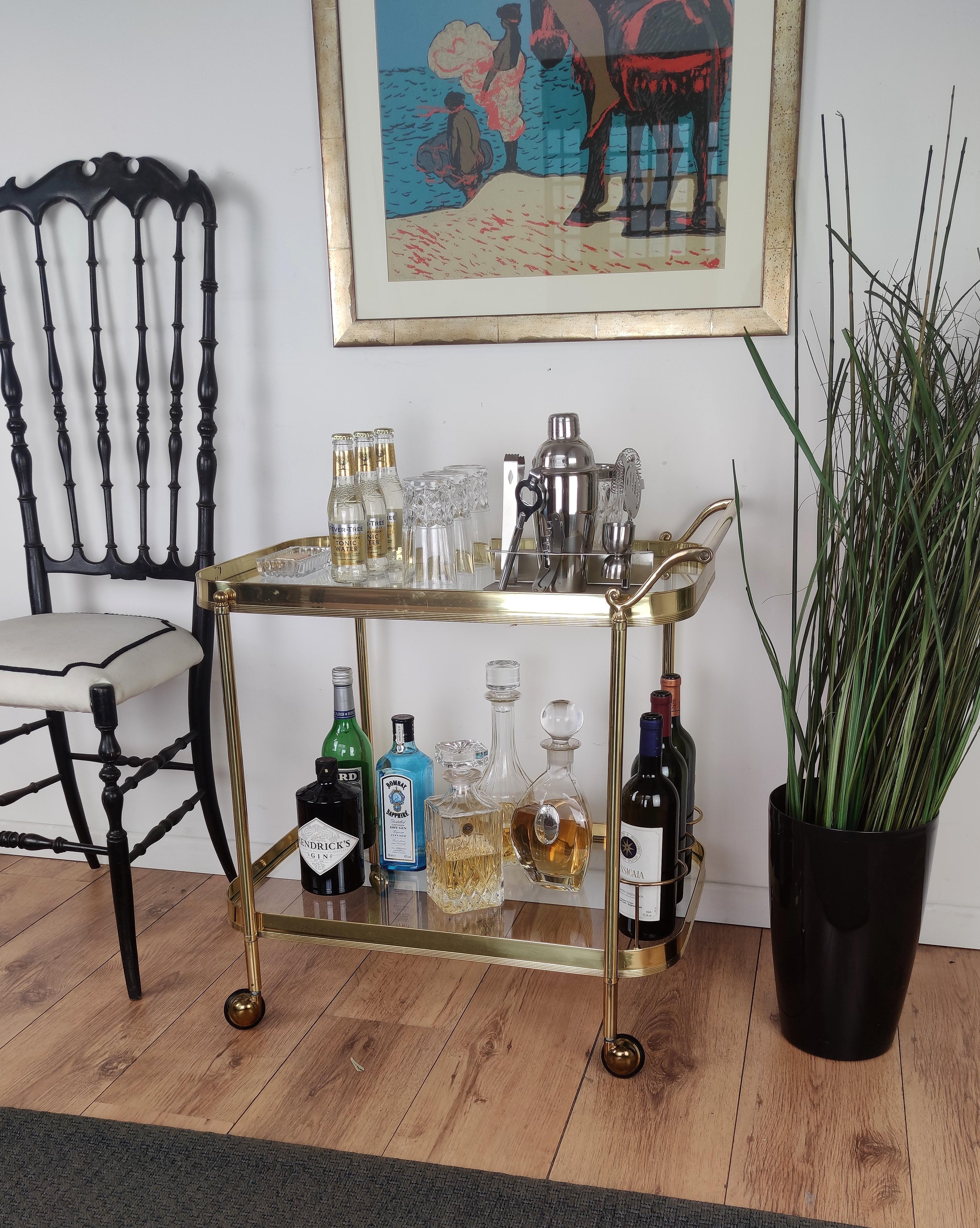 Beautiful and stylish vintage 1970s Italian two-tier brass and glass bar cart with great brass wheels and triple frame for bottle holder. Very good conditions.

A great piece that perfectly adds to every home decor the typical glitz, glamour and
