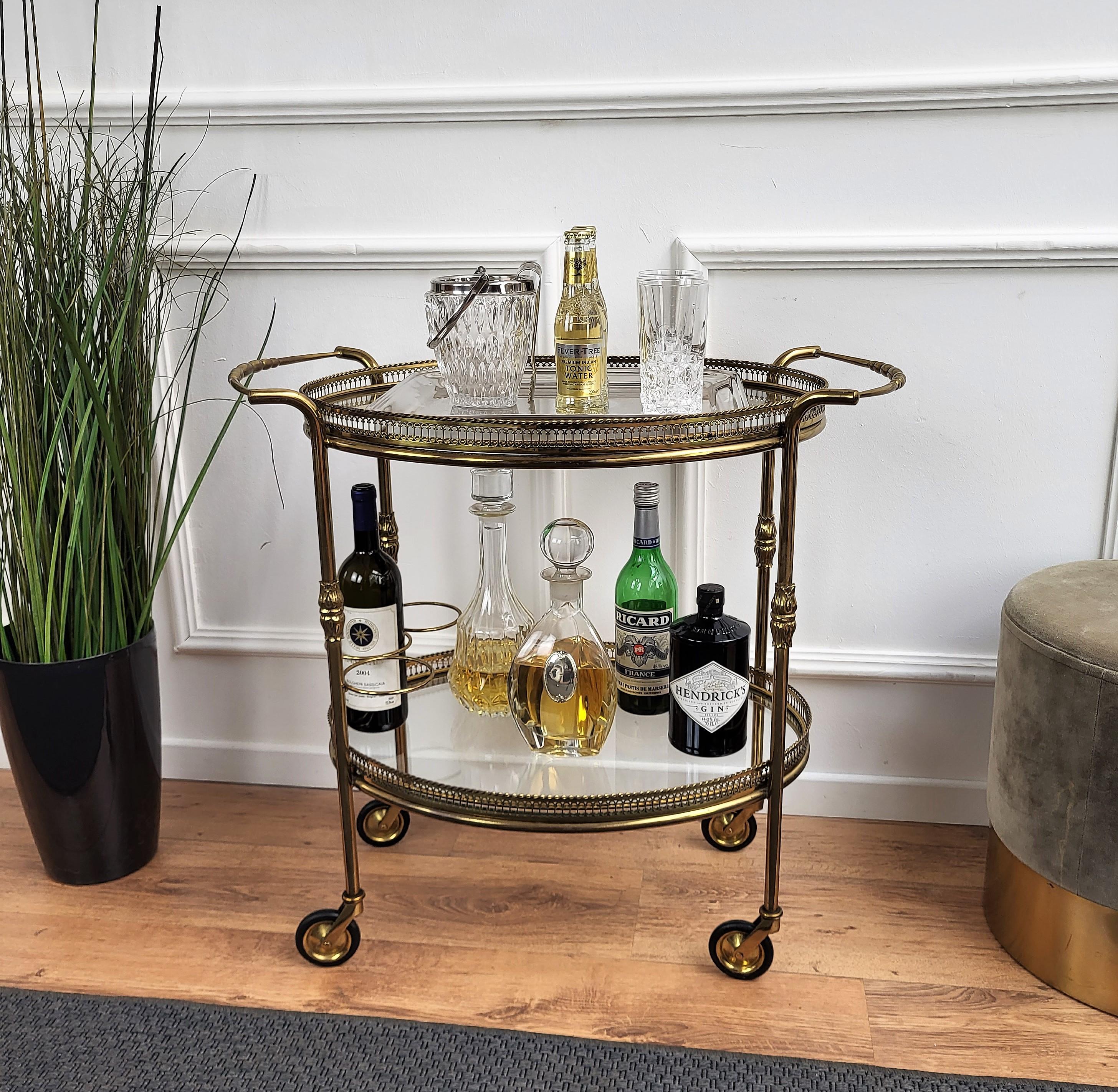 Beautiful and stylish vintage 1970s Italian oval two-tier brass and glass bar cart with great brass wheels and triple frame for bottle holder and double handle. Very good conditions.

A great piece that perfectly adds to every home decor the