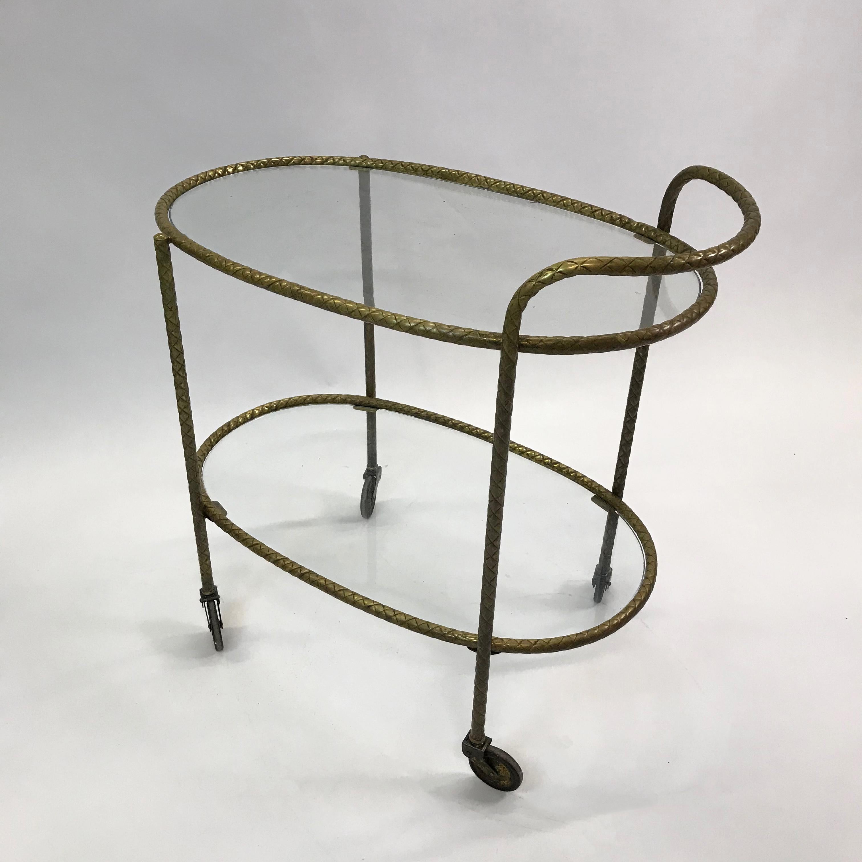 Lovely and unique, Hollywood Regency bar or serving cart trolley features a two-tiered, oval frame of braided, rope motif, brass with glass shelves, handle and wheels for ease of serving.
