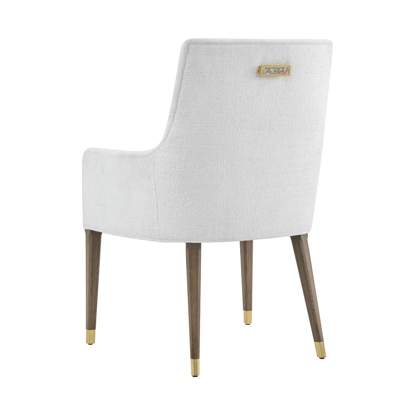 La poltrona imbottita dona un'elegante morbidezza a qualsiasi ambiente da pranzo. Lo schienale e la seduta imbottiti sono stati realizzati su misura per garantire comfort e stile, creando un profilo scultoreo raffinato e invitante.

Le gambe