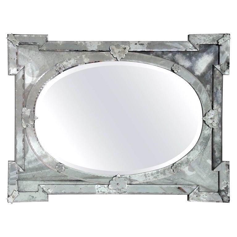 Exquisite large scale Venetian mirror with beveled edges and beautiful hand etched designs throughout. The mirror features a stunning oval center within a shield shaped frame with Smokey glass. Stunning Hollywood Regency Art Deco Era design, mixing