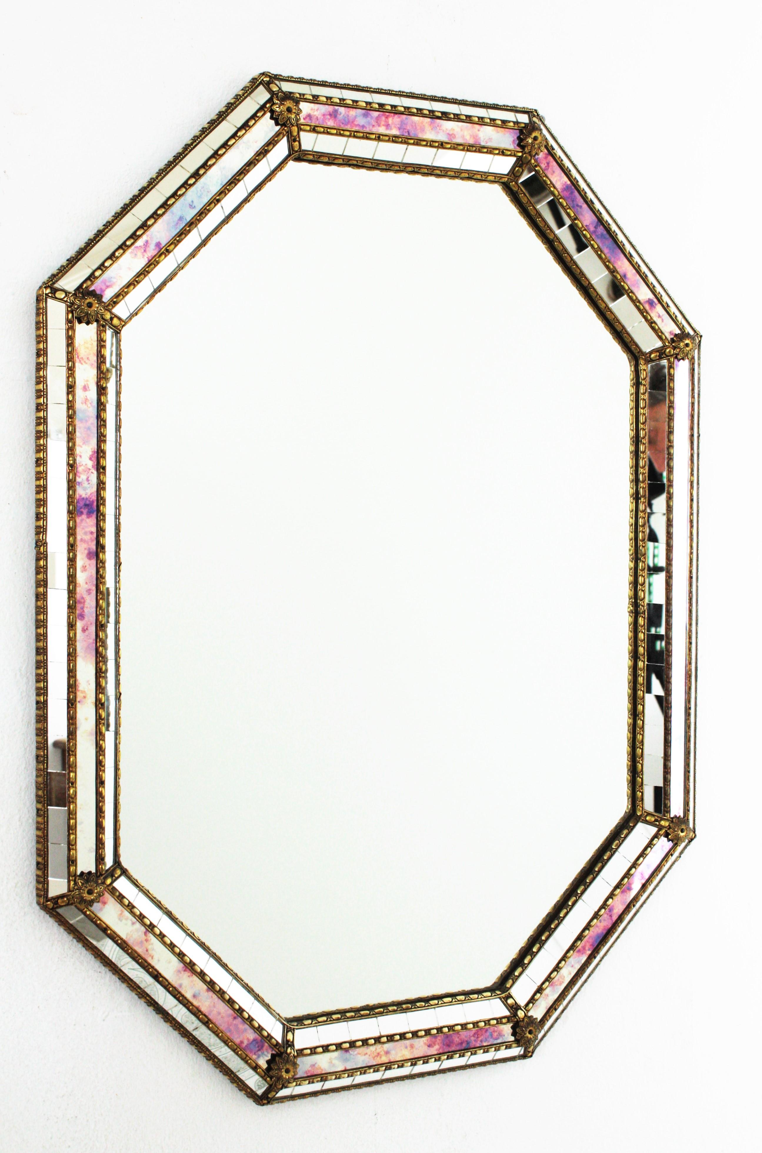 Beautiful Venetian style Hollywood Regency octagonal mirror with iridiscent and mirror glass panels. Spain, 1950s
This glamorous mirror featuring a triple layered mirror frame made of brass. Octagonal form with a beveled frame that has three layers