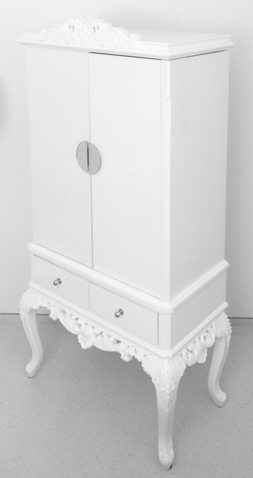 Hollywood Regency style white lacquer cabinet on stand. This cabinet features two shelves and interior long drawer as well as two exterior drawers on base. In good condition. Wear consistent with age and use. Dimensions: 73