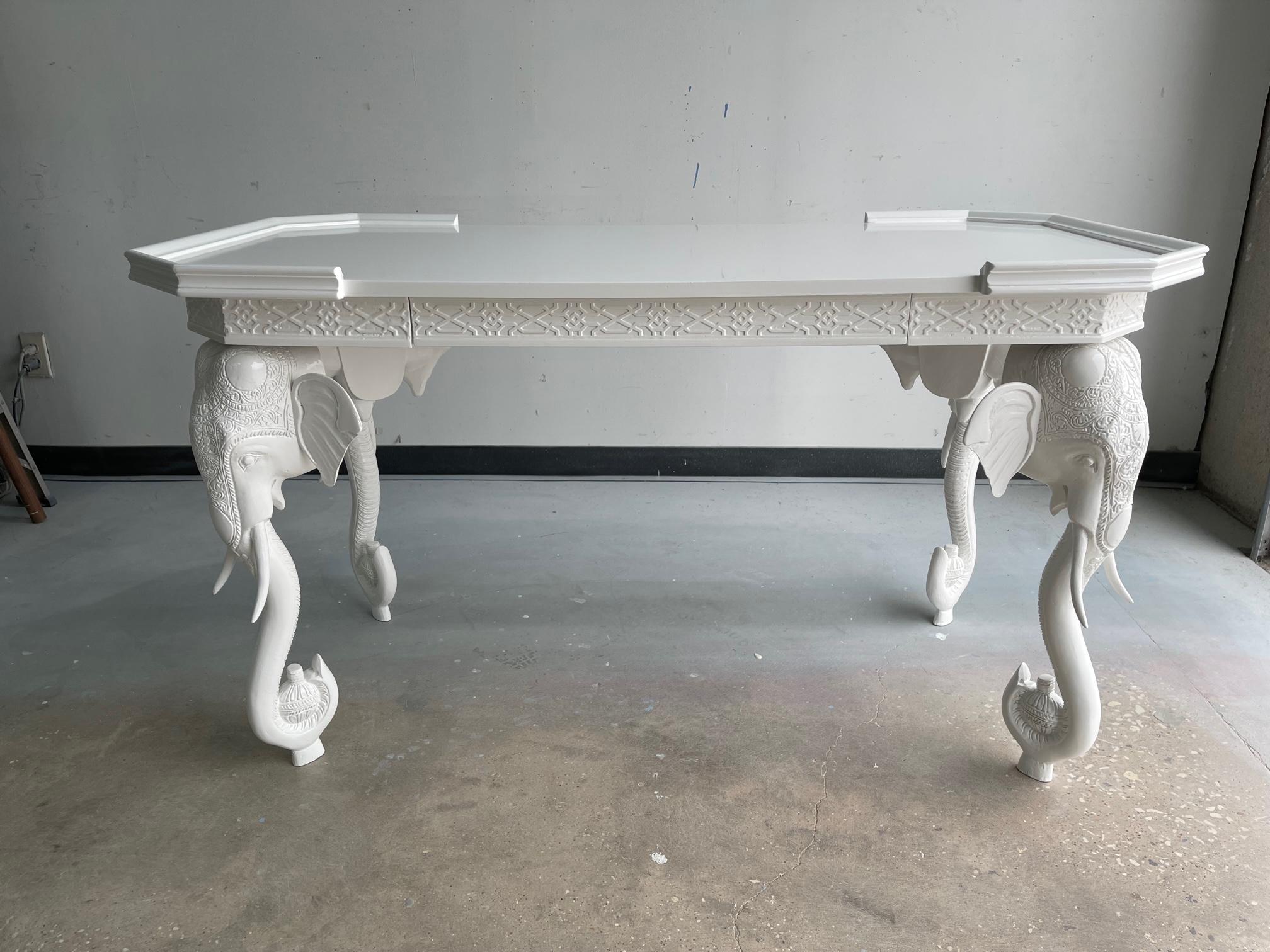 Hollywood Regency white lacquered desk or console by Gampel-Stoll. This stunning British colonial style desk or writing table is supported by four elephant heads with tusks and a hidden drawer. This versatile piece was professionally lacquered, can
