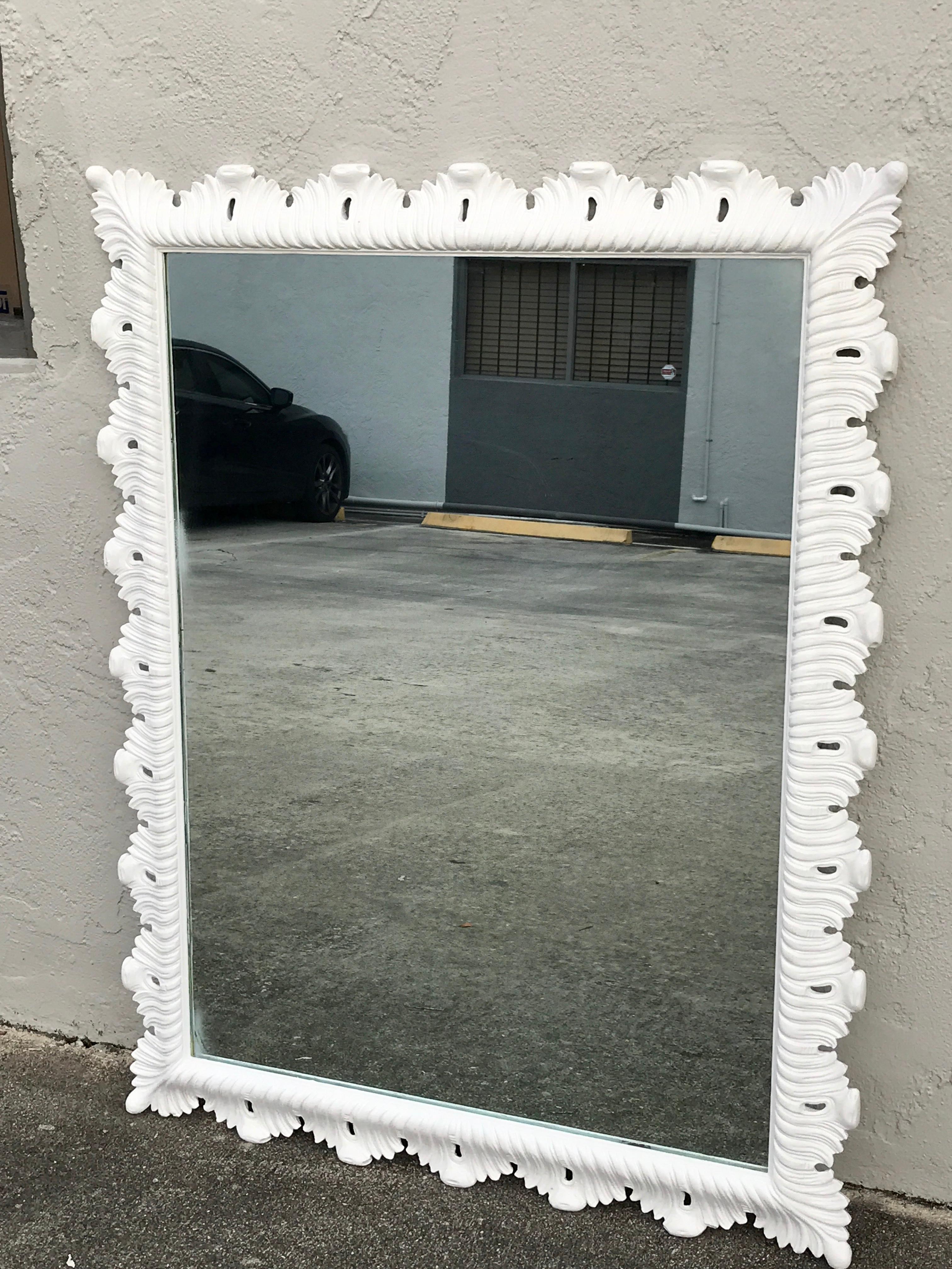 Hollywood Regency white lacquered scalloped mirror, of carved wood with continuous pierced surround, retaining the original mirror.
