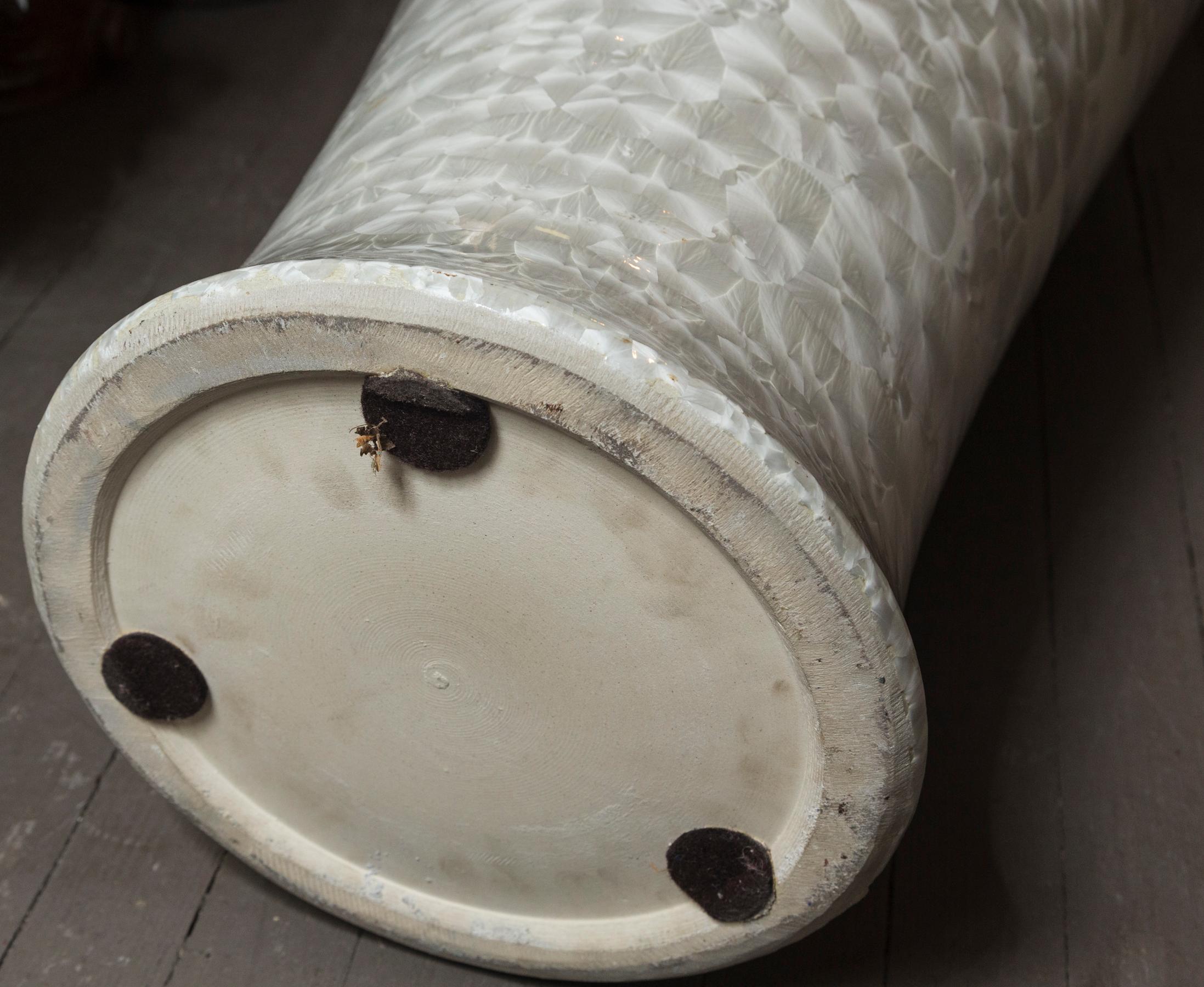 Beautiful and graceful floor vase, glazed white on white, The light shimmers on the vase as it hits. Almost like a mother of pearl or abalone surface. The mouth is 14 inches wide and the base is approximately 10 in diameter.. The diameter of 17 is