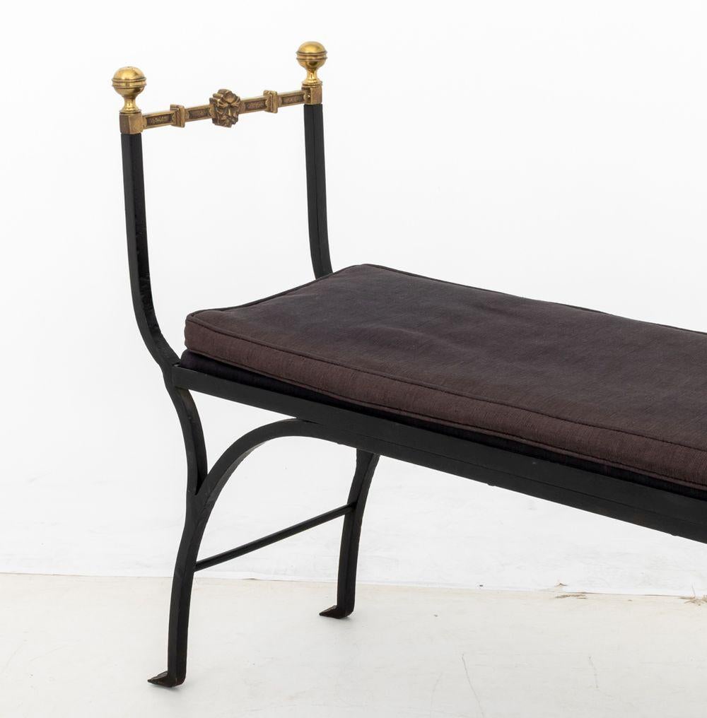 Hollywood Regency Wrought Iron and Brass Bench, with four round finials conjoined by stretches with mask head motif, purple upholstered seat and cushion on four curved legs. 32