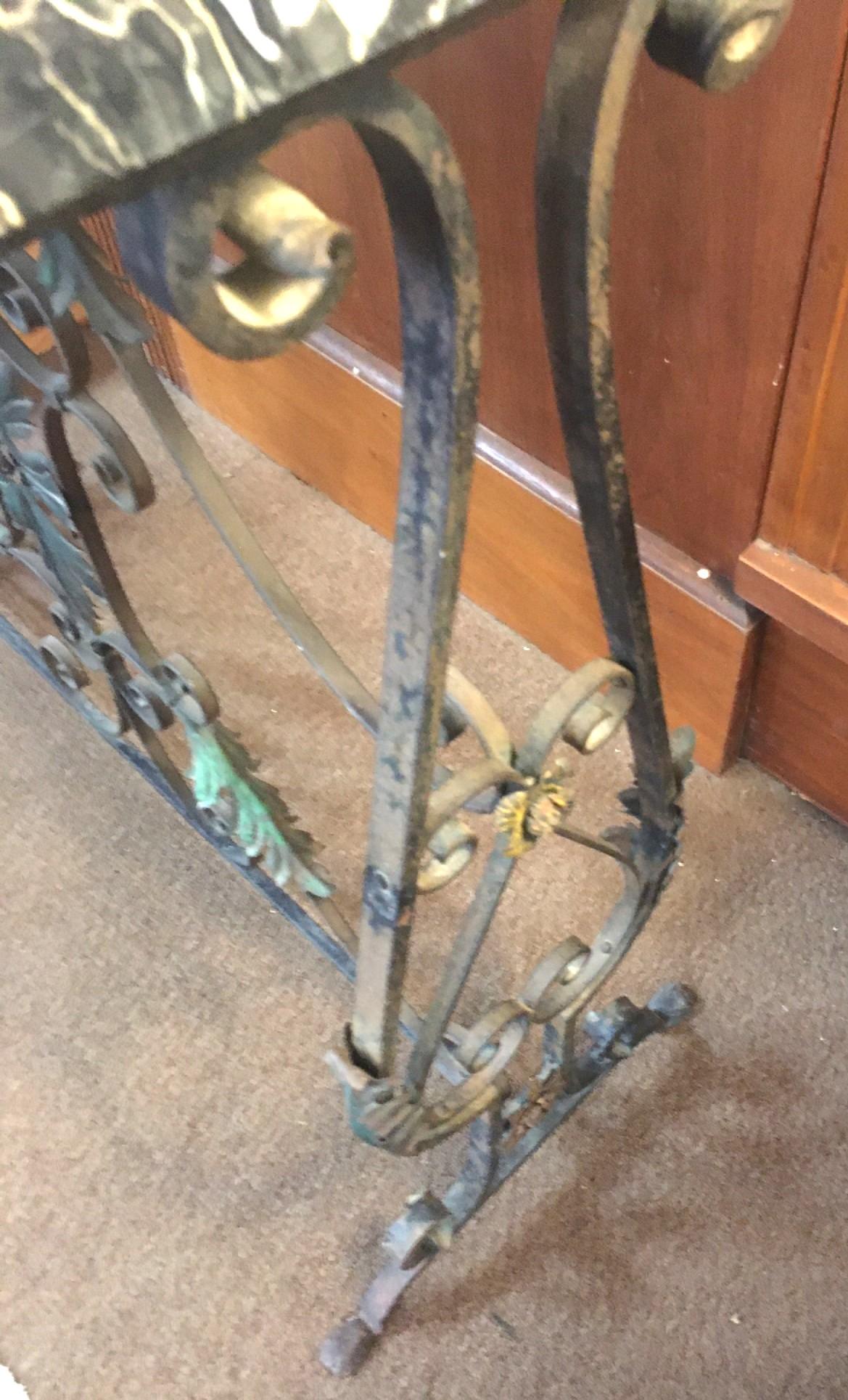 Esta consola francesa de estilo Hollywood Regency tiene una atractiva tapa de mármol Portoro y una base de hierro forjado serpenteante con un diseño floral. La encantadora pátina antigua muestra restos muy tenues de pintura de colores del acabado