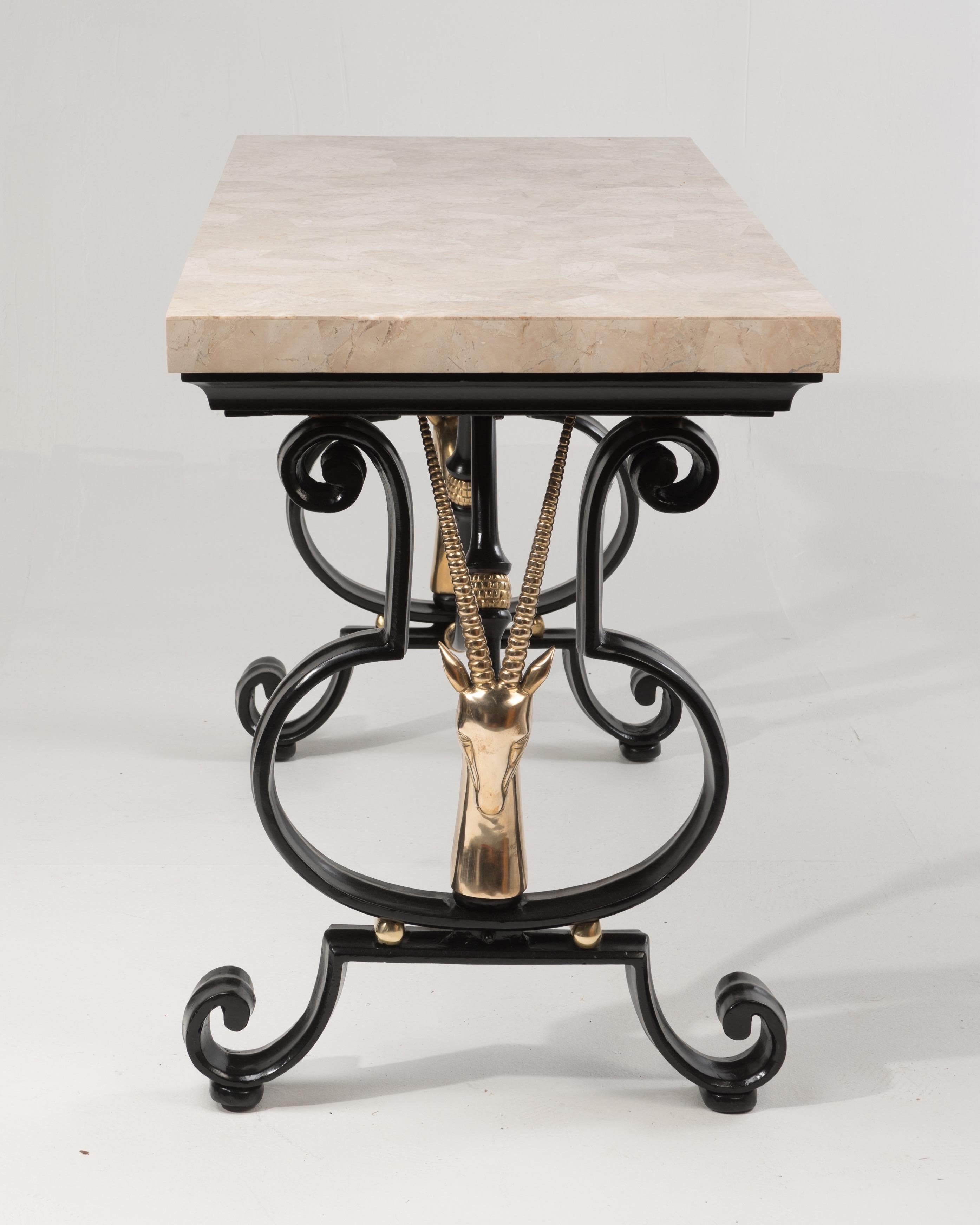 Hollywood Regency console table having a black wrought iron base with glamorous brass gazelles at either end and a white tessellated stone top. Attributed to Maitland Smith and in the manner of Maison Jansen. Beautiful from every angle, finished all