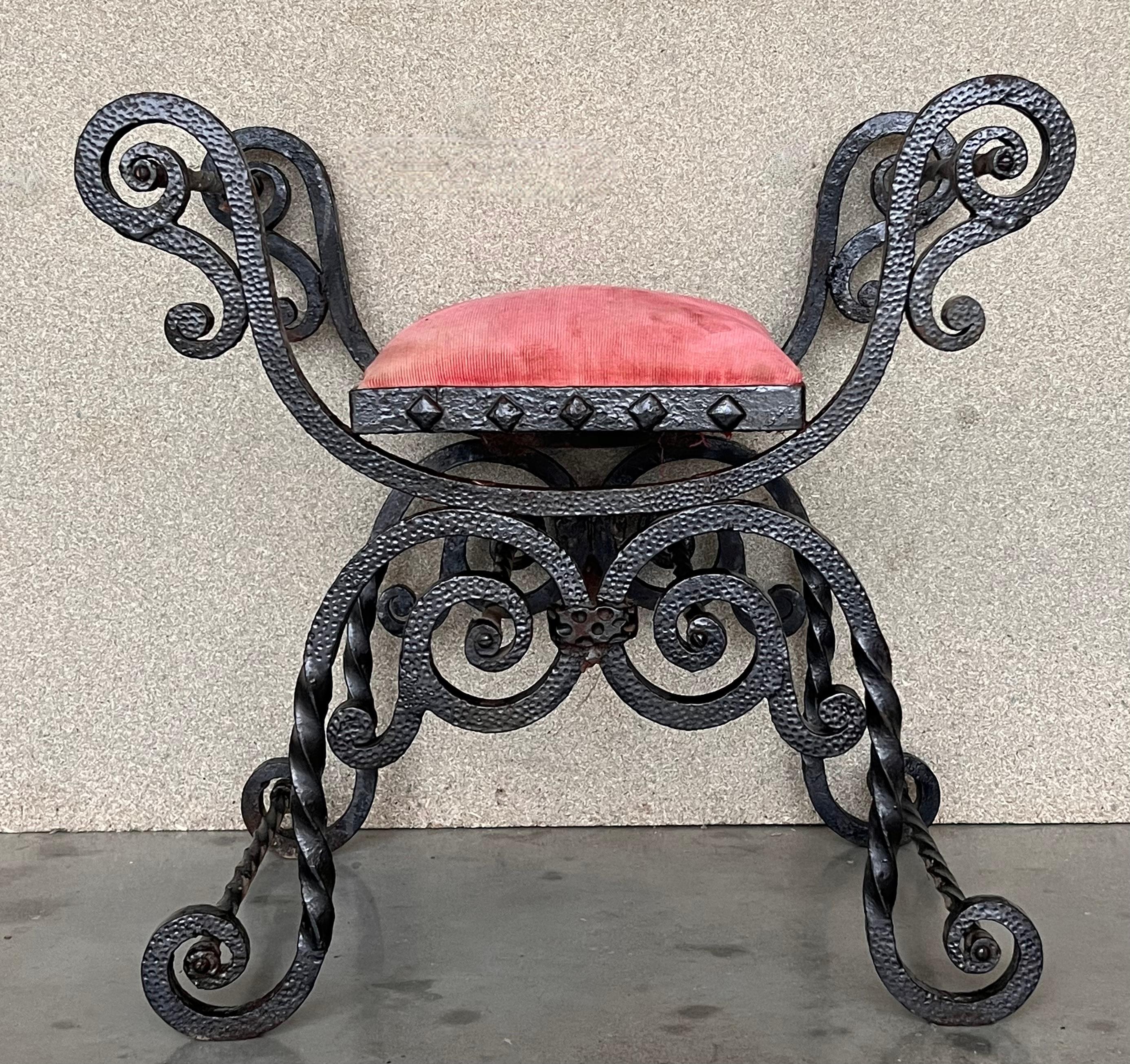 Stylish wrought iron Curule bench made in the neoclassical taste. Featuring an X-form design with scrolled arms and feet. These bench are also known as Dante chairs, Savonarola chairs, and throne benches. The wrought iron has a tough patinated metal