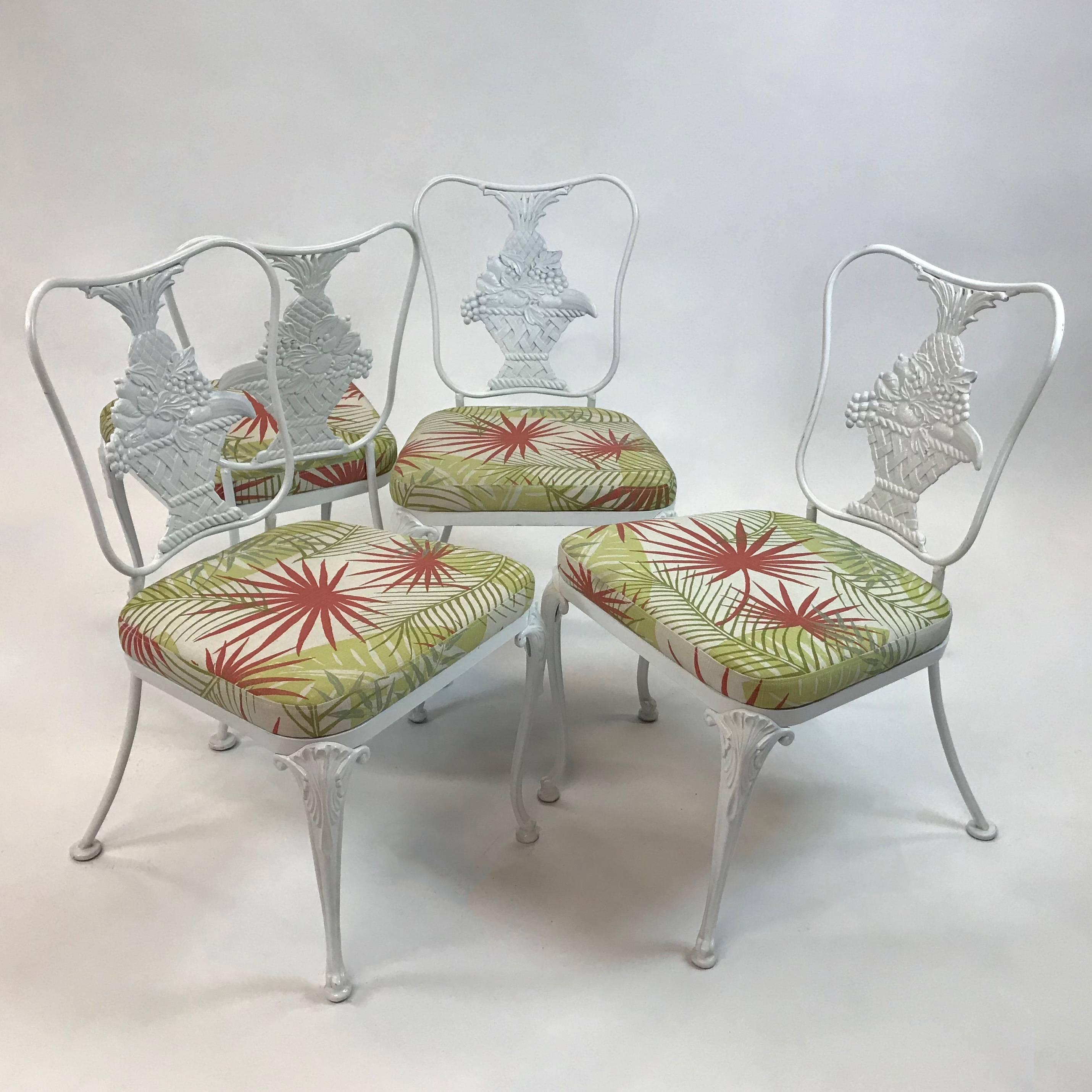 Set of four, Hollywood Regency, patio chairs feature painted, wrought iron, pineapple motif frames with newly upholstered seats. The chairs are perfect for a sun room or covered patio. The seats are not removable.