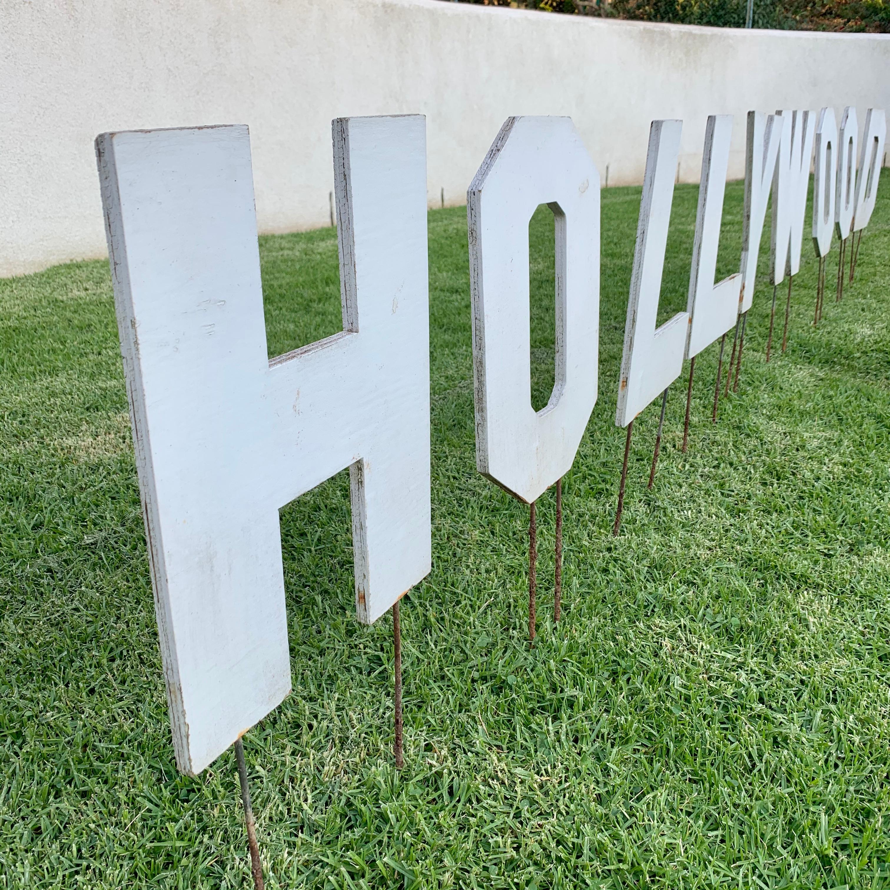 Fun piece of Los Angeles artwork. Hollywood sign made as an artist's model to make larger versions at a later time. Letters are perfect scale. Made of wood with metal rods attached to plant into the ground. Average letter size is 10.5