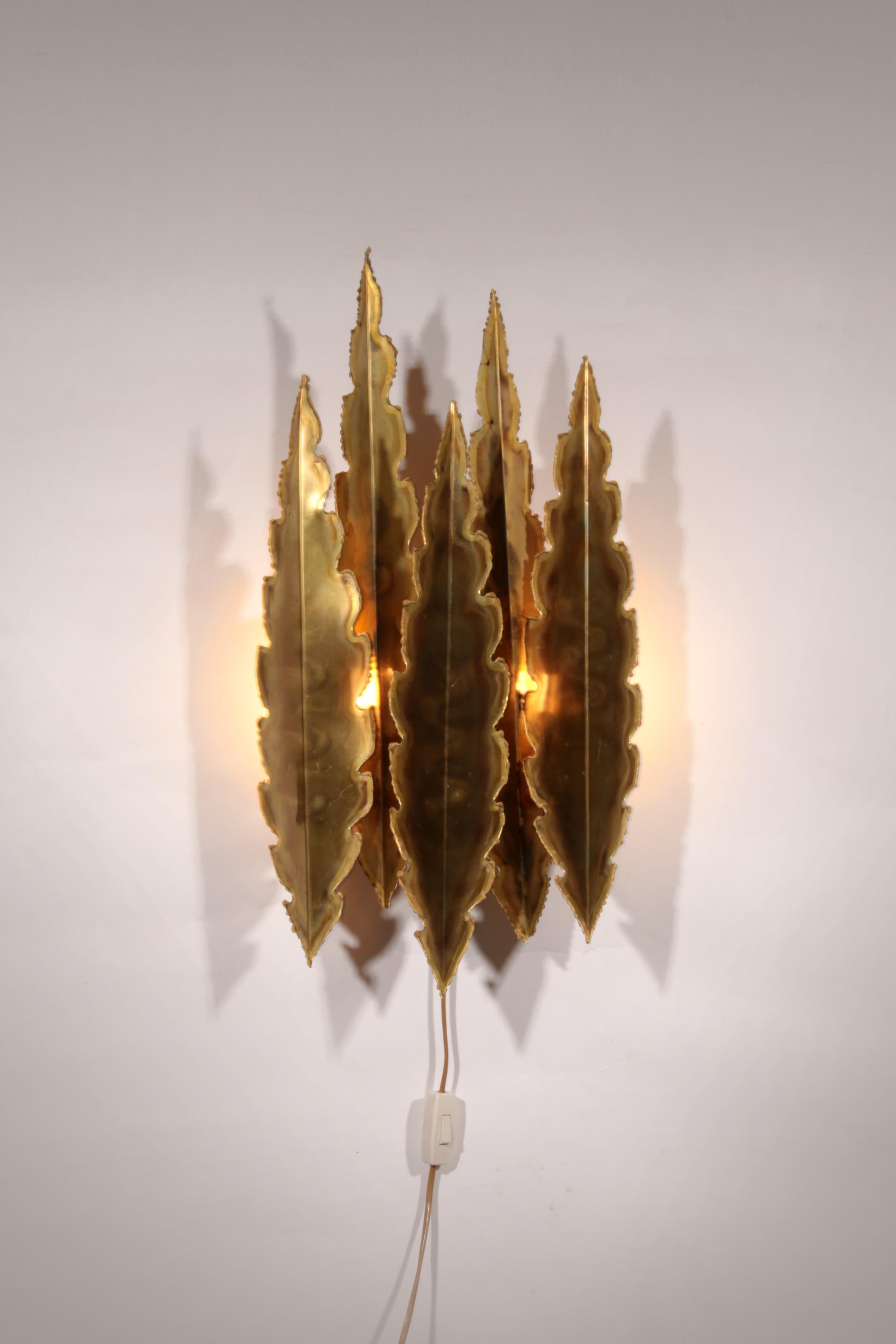 

Cette exquise applique murale en laiton, conçue par le célèbre designer danois Svend Aage Holm Sørensen dans les années 1960, met en valeur des feuilles de laiton fabriquées à la main et un savoir-faire exceptionnel. Fabriqué au Danemark, il