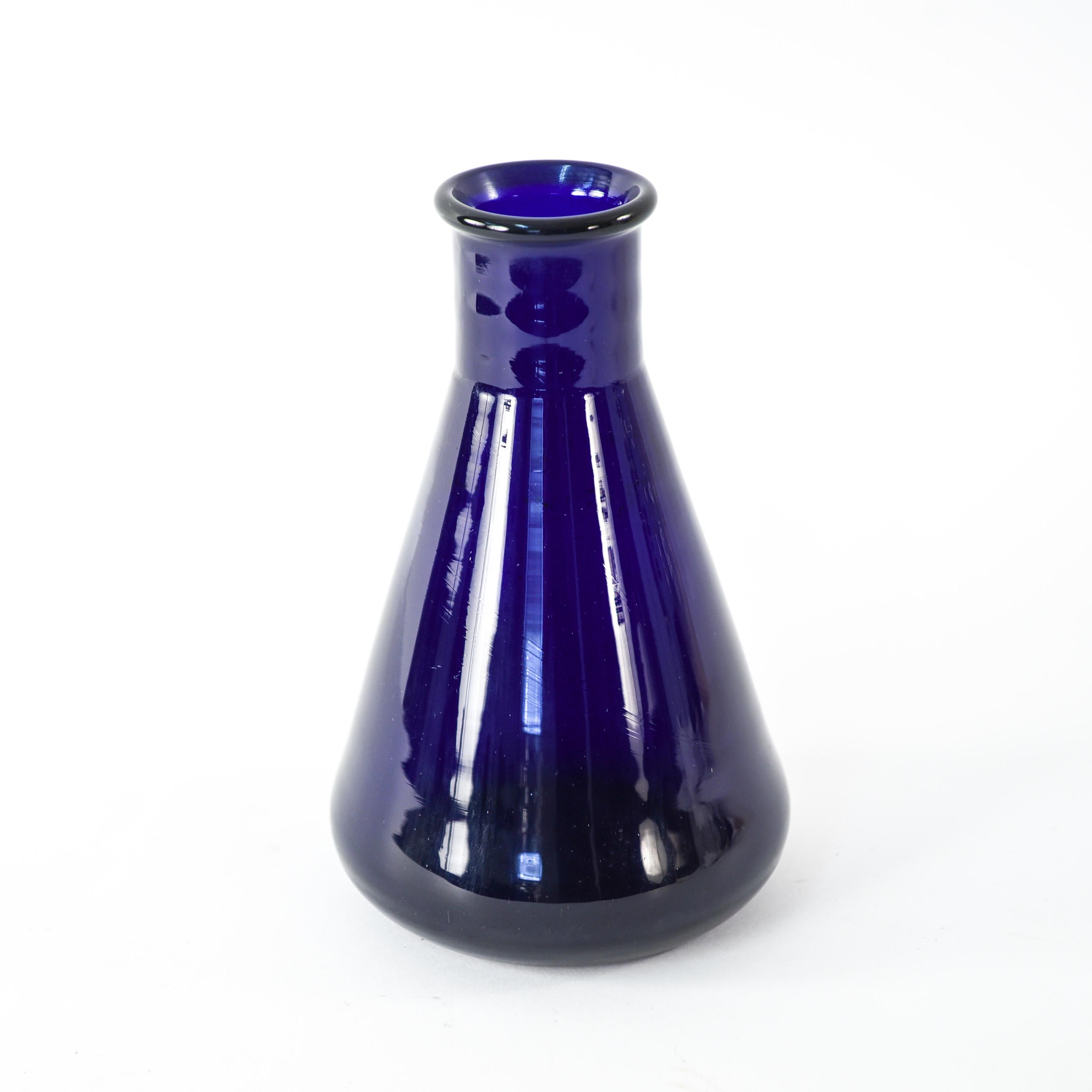 This blue glass Danish midcentury Holmegaard vase has a charming appeal to it. Its slender neck and conical base almost give it a resemblance to a scientific beaker, but the color reminds of the decorative nature. Marked underneath: Struers.