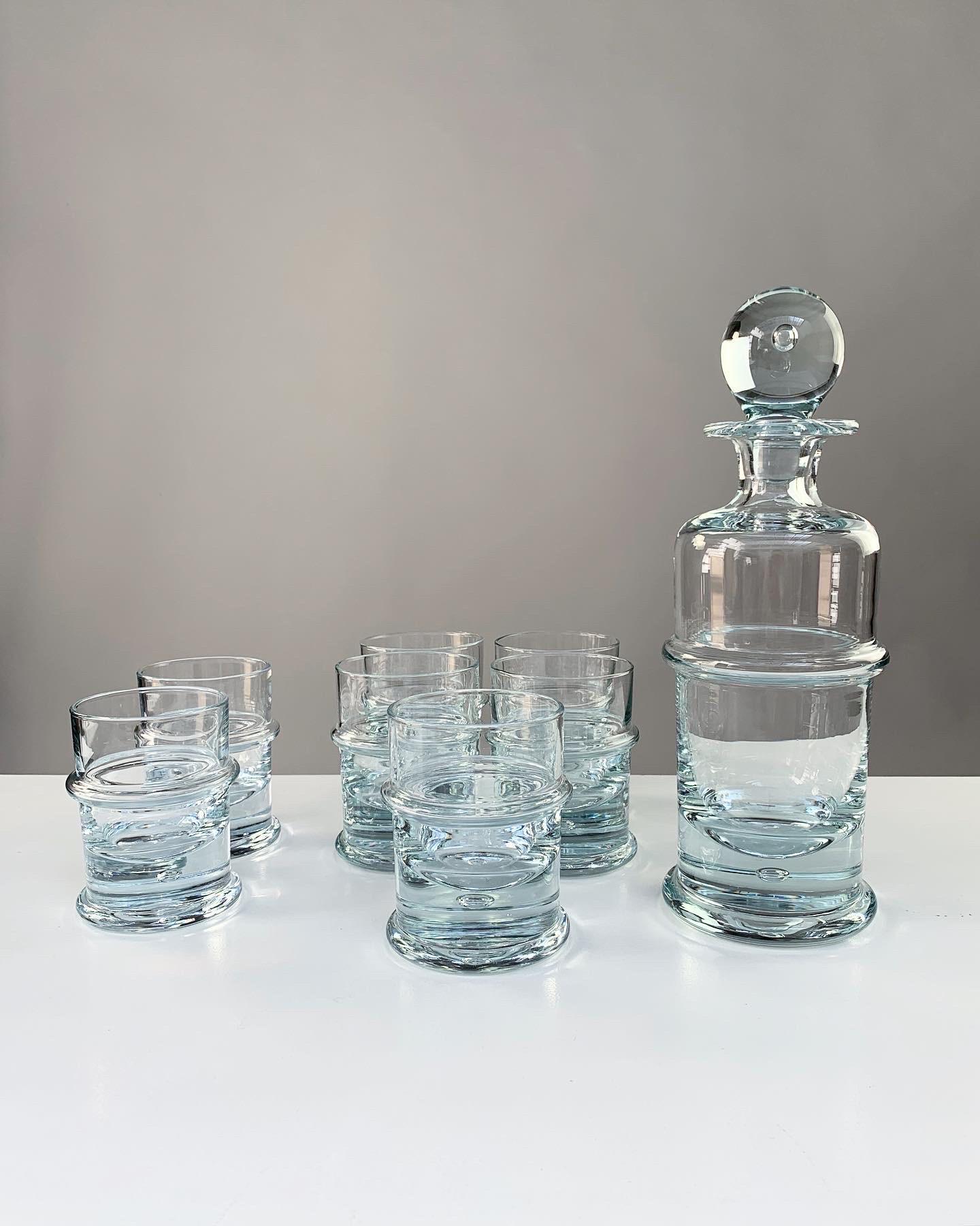Sidse Werner bottle decanter with seven tumber glasses, model ‚Regiment‘ designed in 1972 for Holmegaard glassworks in Denmark.

Made of heavy crystal glass, each piece has an enclosed bubble in the bottom, including the bottle stopper.

The