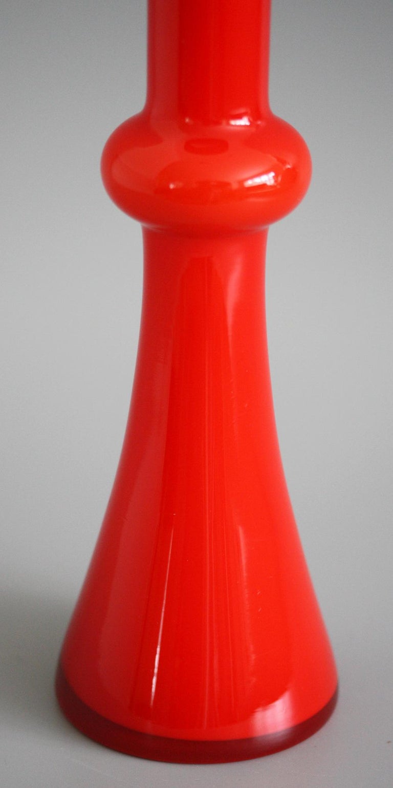 A very stylish Danish Holmegaard midcentury red overlay art glass knuckle vase designed by Christer Holmgren and dating from around 1968. The tall slender vase is part if the Carnaby range and has a wide skirted base which narrows to a rounded