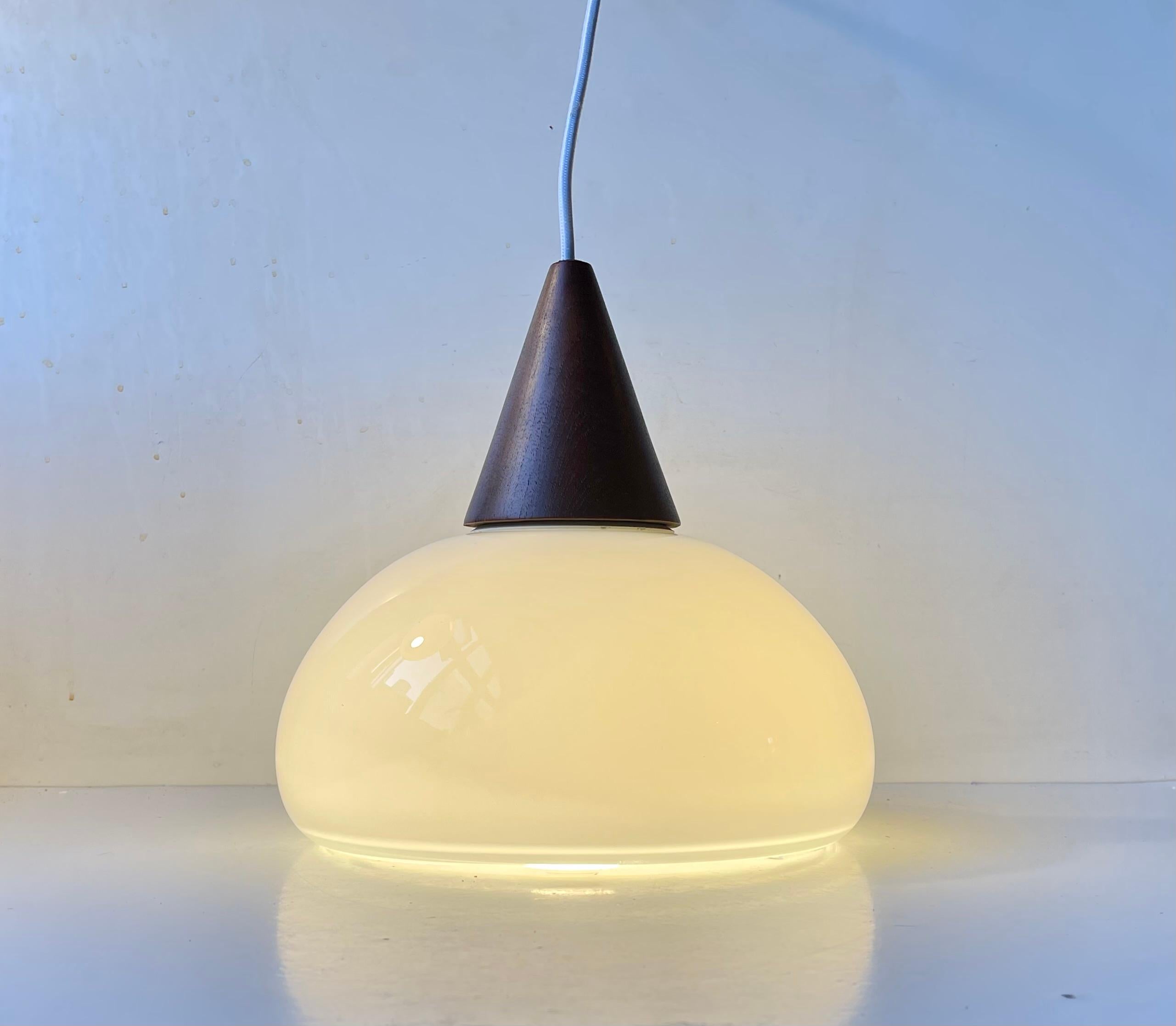 A rare hand-blown cased white opaline glass pendant light designed by Per Lütken and manufactured by Holmegaard in Denmark during the late 1970s or early 80s. It is called Sunset and is characterized by its mushroom shape and reflective bottom edge