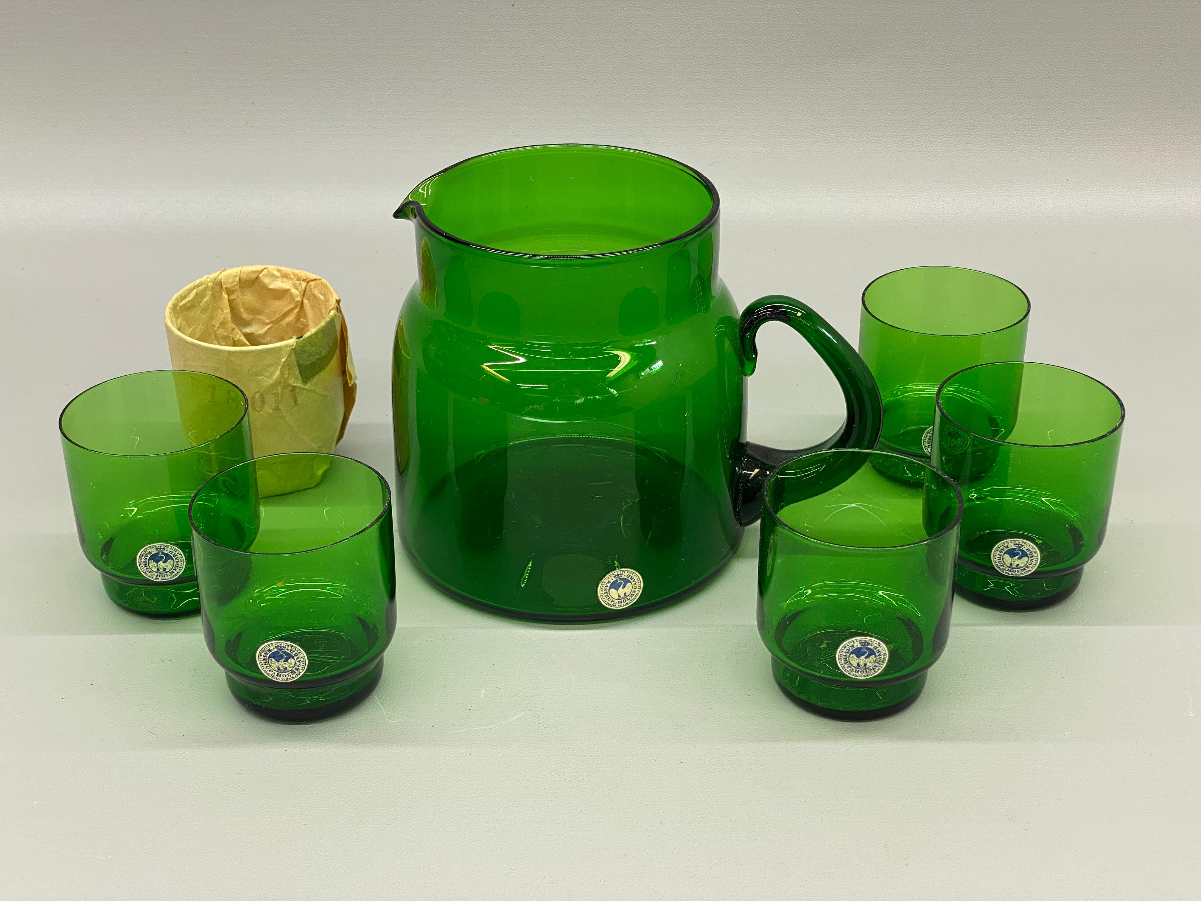 Ein feines und makelloses Set aus sechs smaragdgrünen Gläsern und einer Karaffe. Die Gläser und der Krug tragen noch die originalen Papieretiketten: By Appointment to H. H. The King of Denmark, Made in Denmark, Kastrup, Holmegaard, 62. Ein wahrer