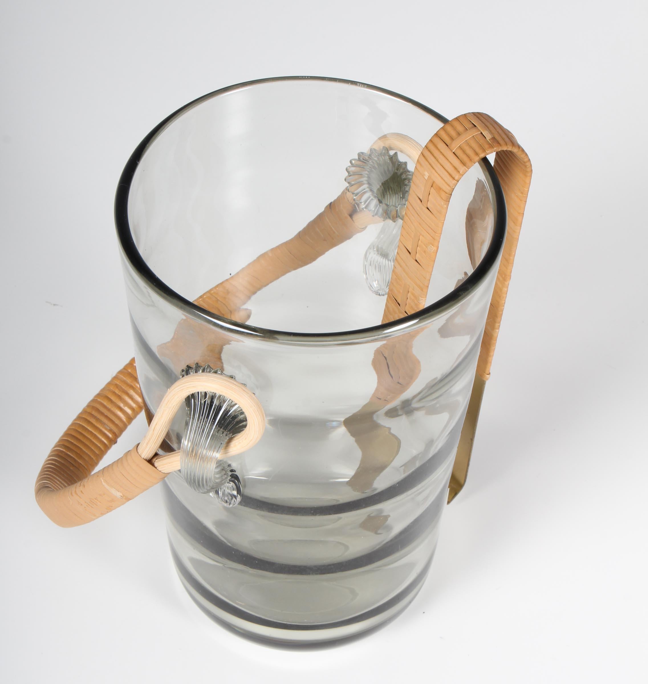 Holmegaard ice bucket in glass with cane handle. Icecube thong in brass.

Made by Holmegaard in the 1960s.