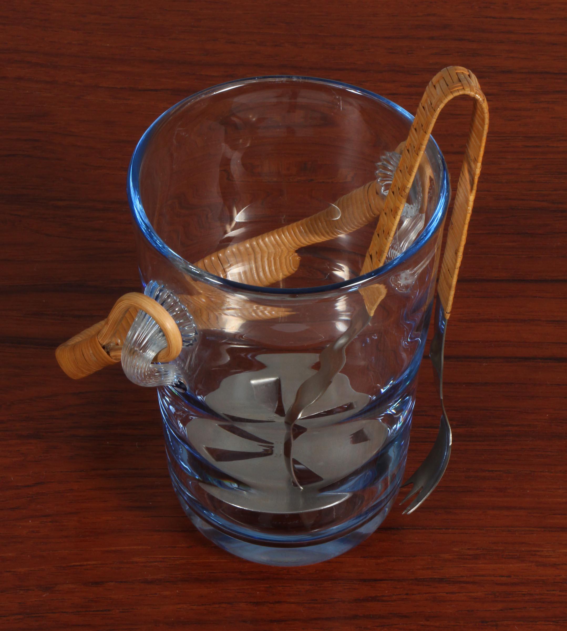 Holmegaard ice bucket in glass with cane handle.

Made by Holmegaard in the 1960s.