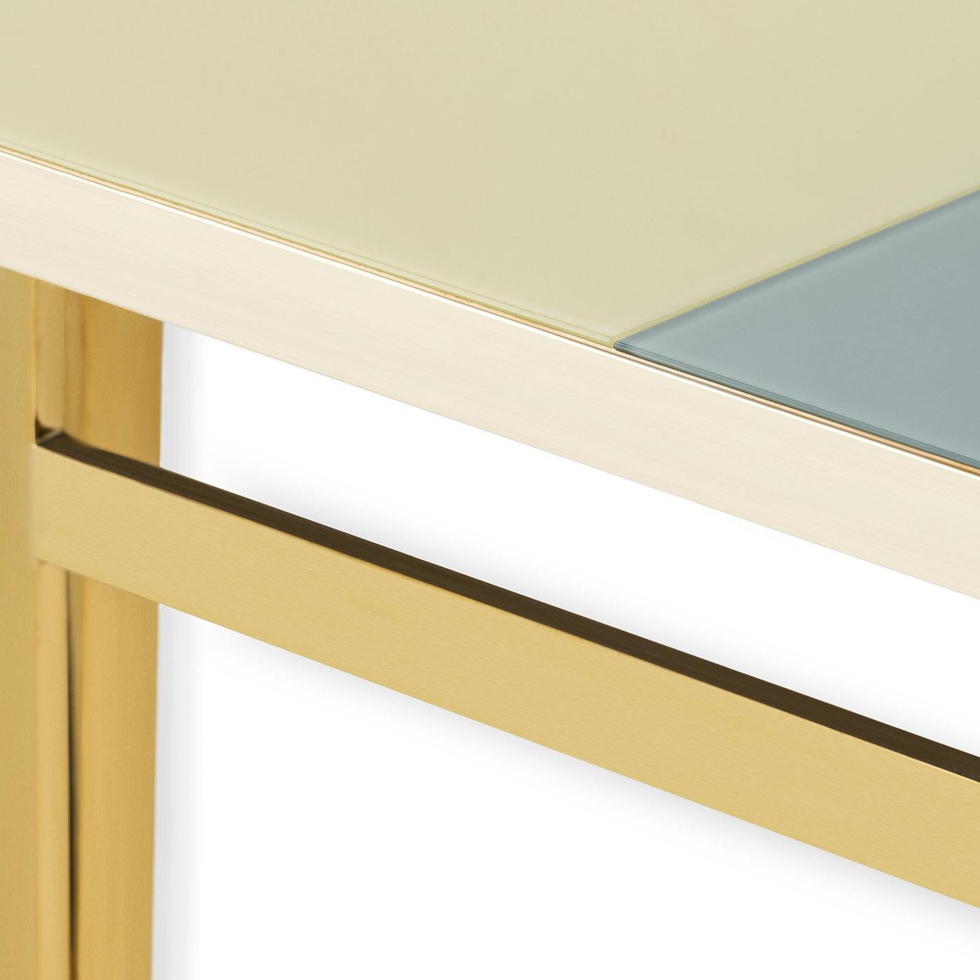 This compact and on-trend console brings geometric flair to an entirely new level of refinement, where it meets the preciousness of first-rate glass. Raised on a luminous brass structure comprising three supporting legs per side, the top features a