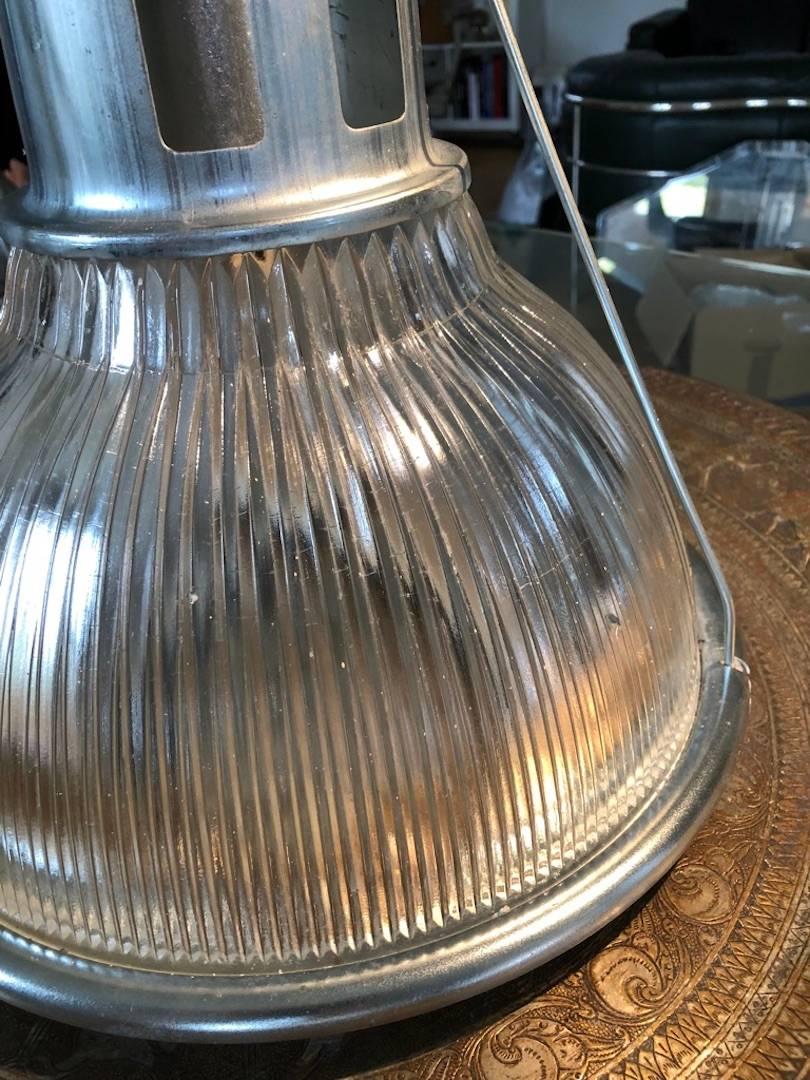 This industrial light has a beautiful prismatic glass which casts the light evenly around the shade. It presents the advantage of having a hook from which to hang it at the chosen height. It is made and labelled by Holophane. Holophane is renown