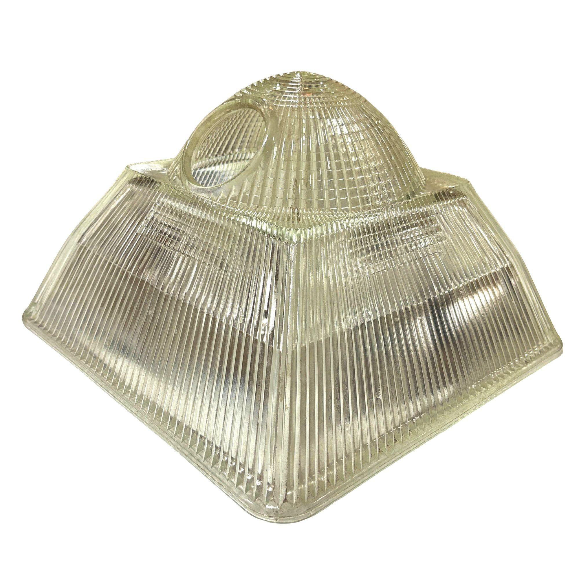 Il paralume della plafoniera in vetro Holophane, spesso a forma di nervatura o prisma, fornisce un'illuminazione diffusa in stile industriale. La sua struttura robusta e il suo design classico la rendono una scelta senza tempo per gli interni