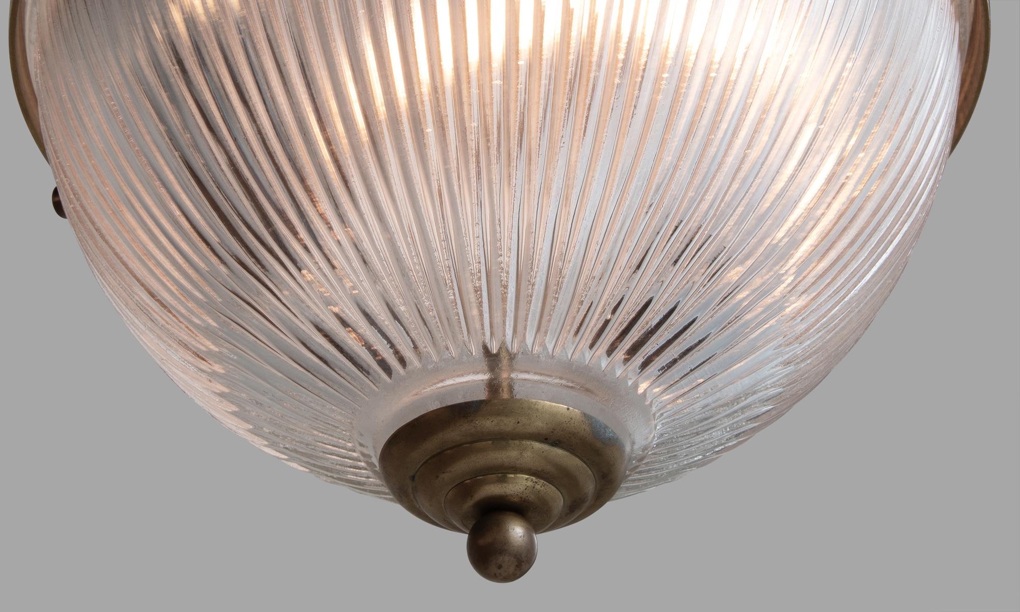 Holophane globe pendants, England, 20th century.

Large two-part Holophane fixtures with brass cage and fitter.