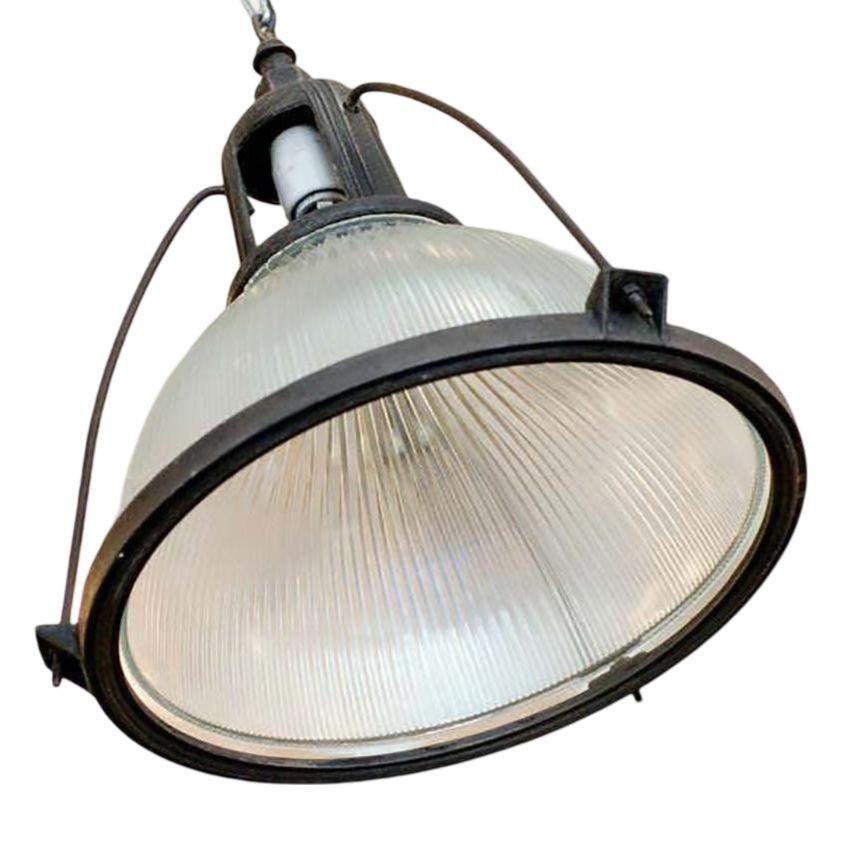 Questa lampada a sospensione industriale ma elegante degli anni '40 presenta un paralume in vetro Holophane. La sospensione è collegata a un involucro di alluminio fissato alla parte superiore dell'apparecchio.

Un apparecchio da soffitto in vetro