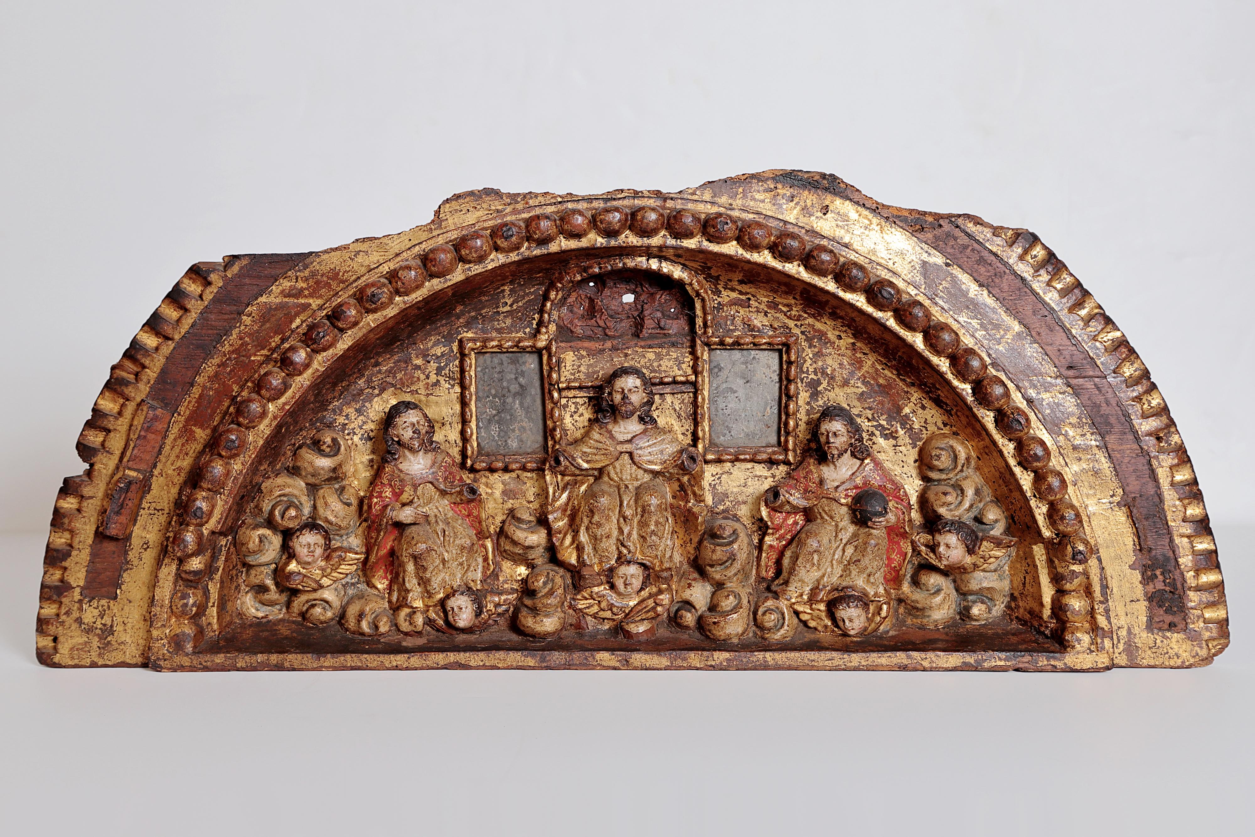 An elaborate giltwood carved fragment, semi-circular in shape, of the Holy Trinity in front of windows surrounded by cherubim, carved beaded border, Italy, late 17th century.

Losses to the top, as pictured

Missing hands, as pictured.