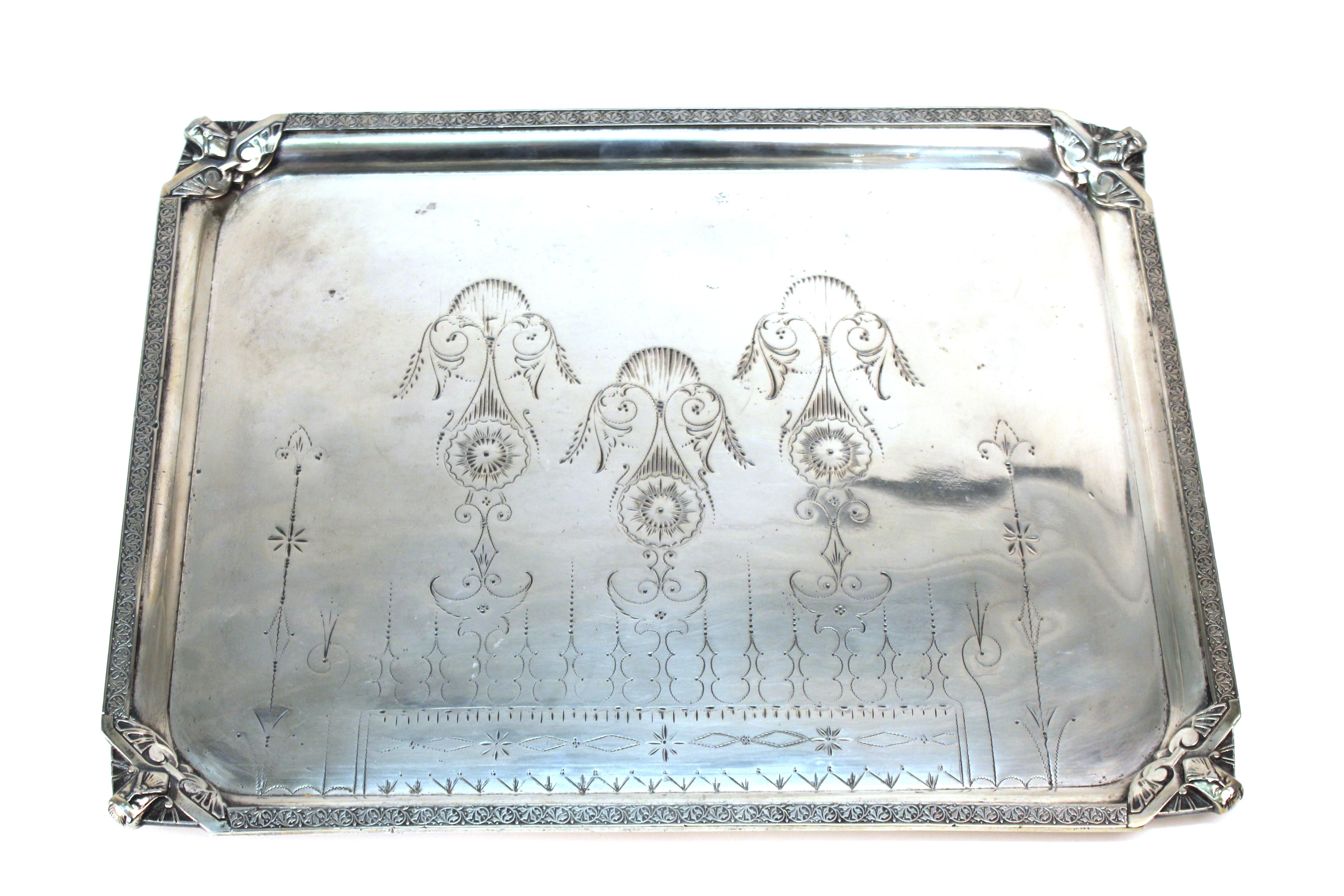 English Victorian silver plated tray with elaborate engraving made by Homan Silver Plate Company. The piece has decorative mascarons in each corner and is likely made in the late 19th century. In great antique condition with age-appropriate wear and