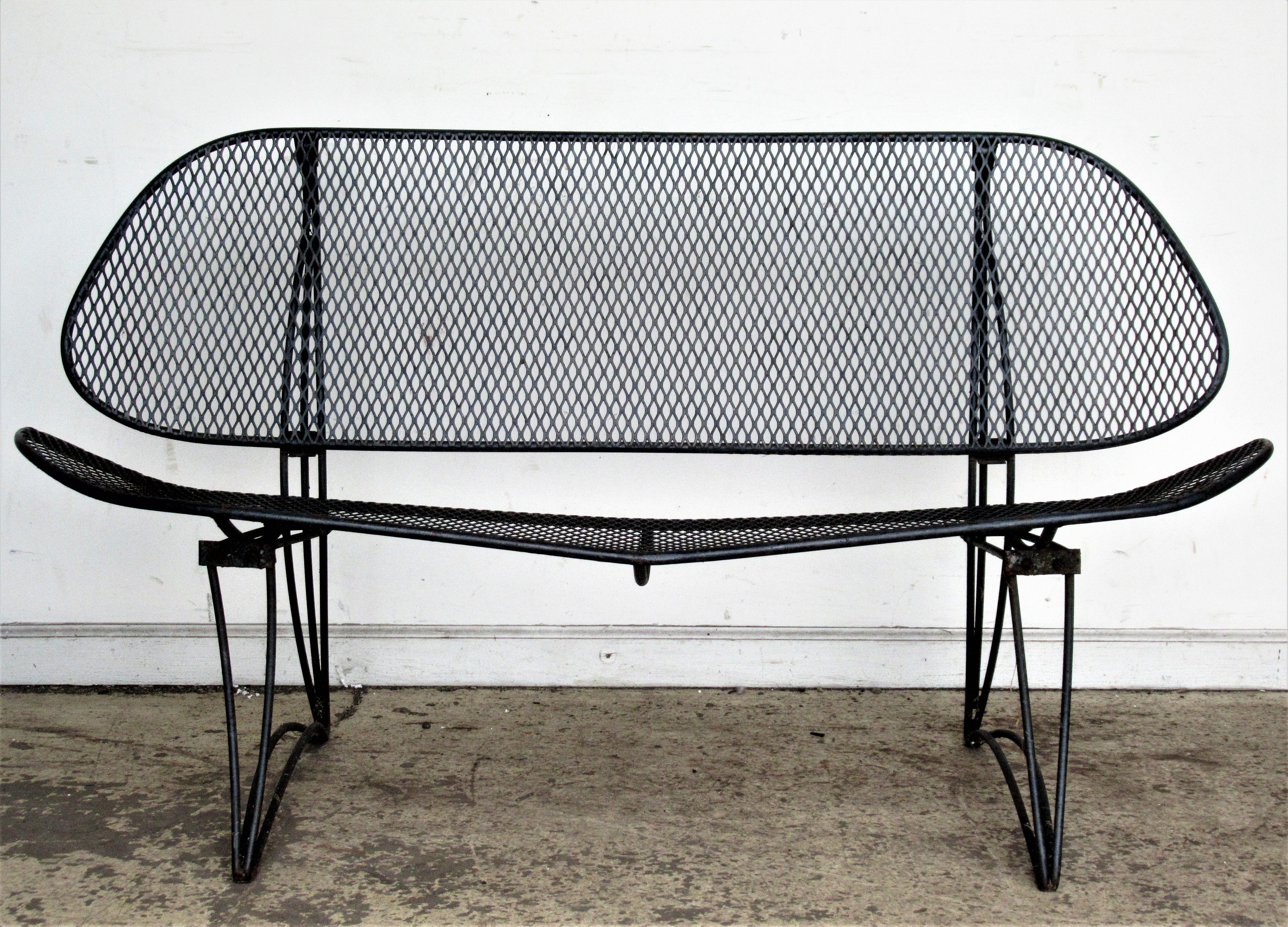A set of modernist wrought iron diamond mesh clamshell design patio garden furniture consisting of a settee and two lounge chairs ( one is a bouncer )  in original black enamel painted factory finish with minor wear. Often attributed to Maurizio