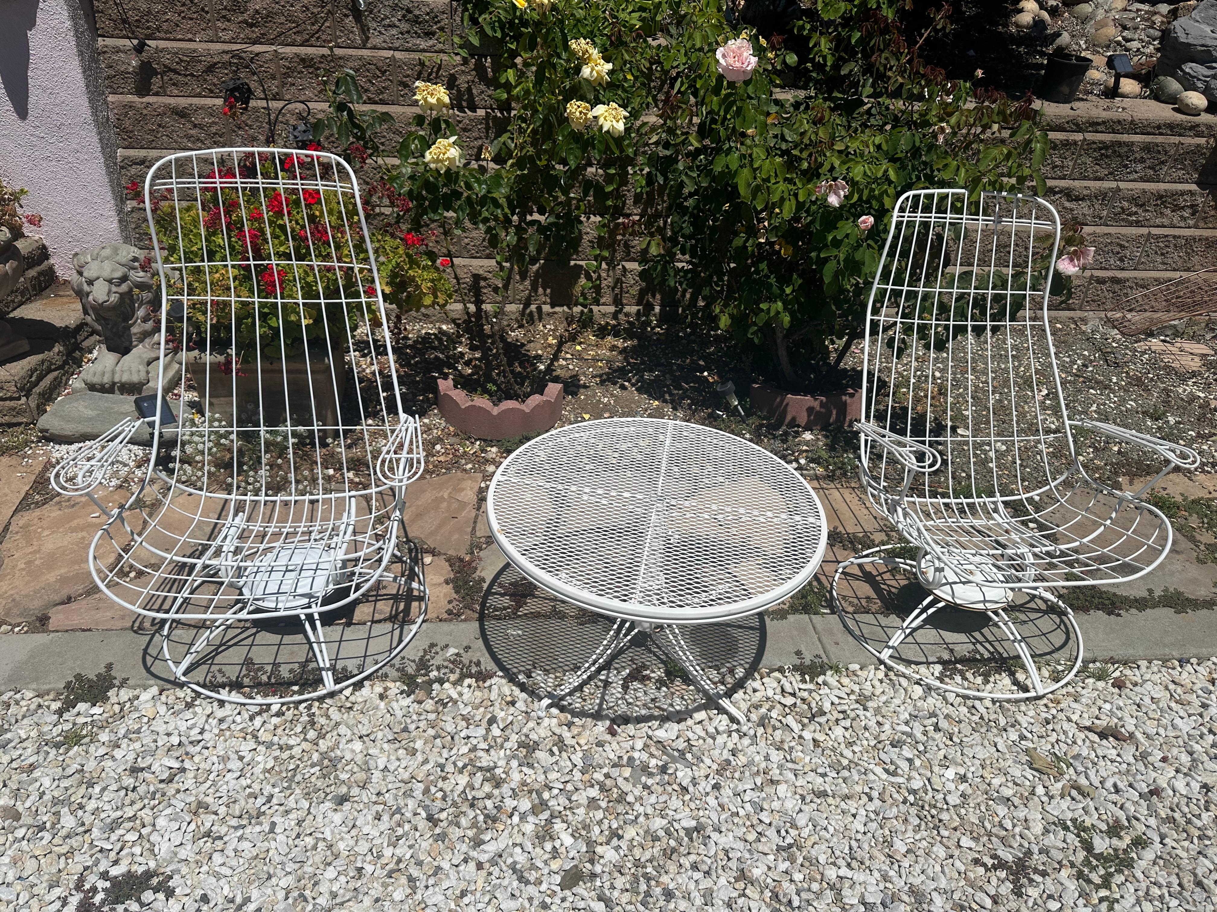 Vintage mid century patio set by Homecrest.
3 piece set, wired armchairs that swivel and rocks and an adjustable height coffee table
made of  wrought iron 

set includes
2 high back armchairs 
1 coffee table

Circa 1960's 
Chairs measure:
 43