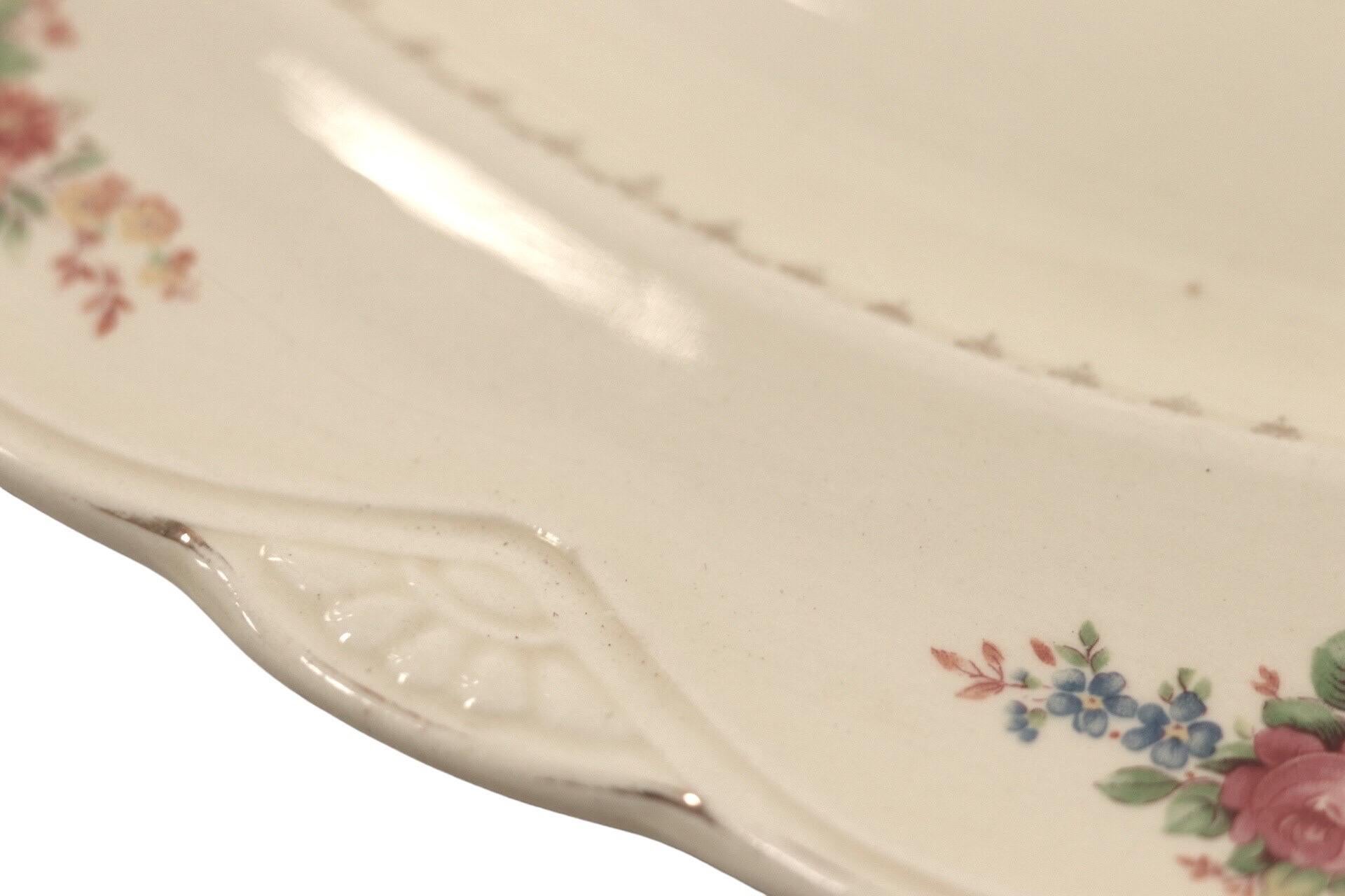 An oval serving platter in the Marigold pattern, made by Homer Laughlin circa 1940. The rich ivory body has a gilt lined oval edge, embossed with a scalloped shape inset with marigolds. The rim is decorated with floral sprays in pink, orange,