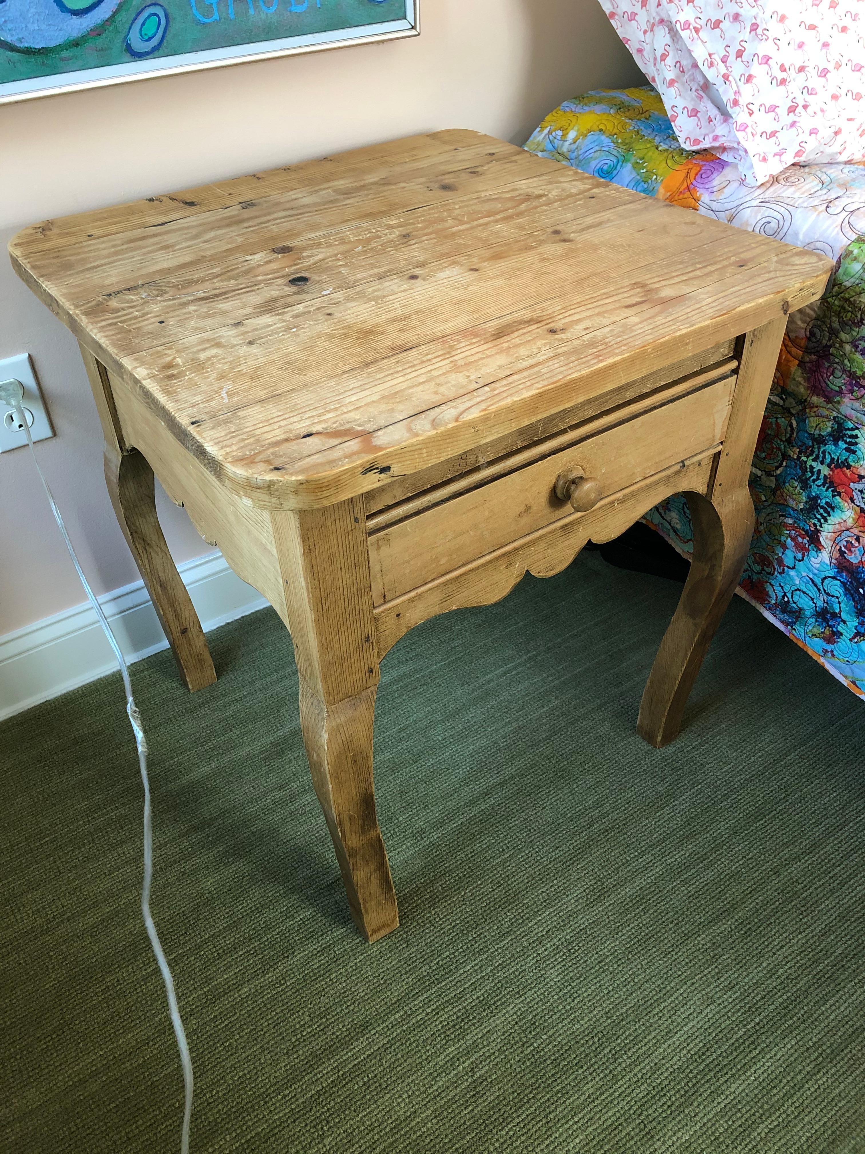 Homey and simple substantial end table or night stand made of natural unfinished pine having single drawer, handsome grain, scalloped apron and cabriole shaped legs.