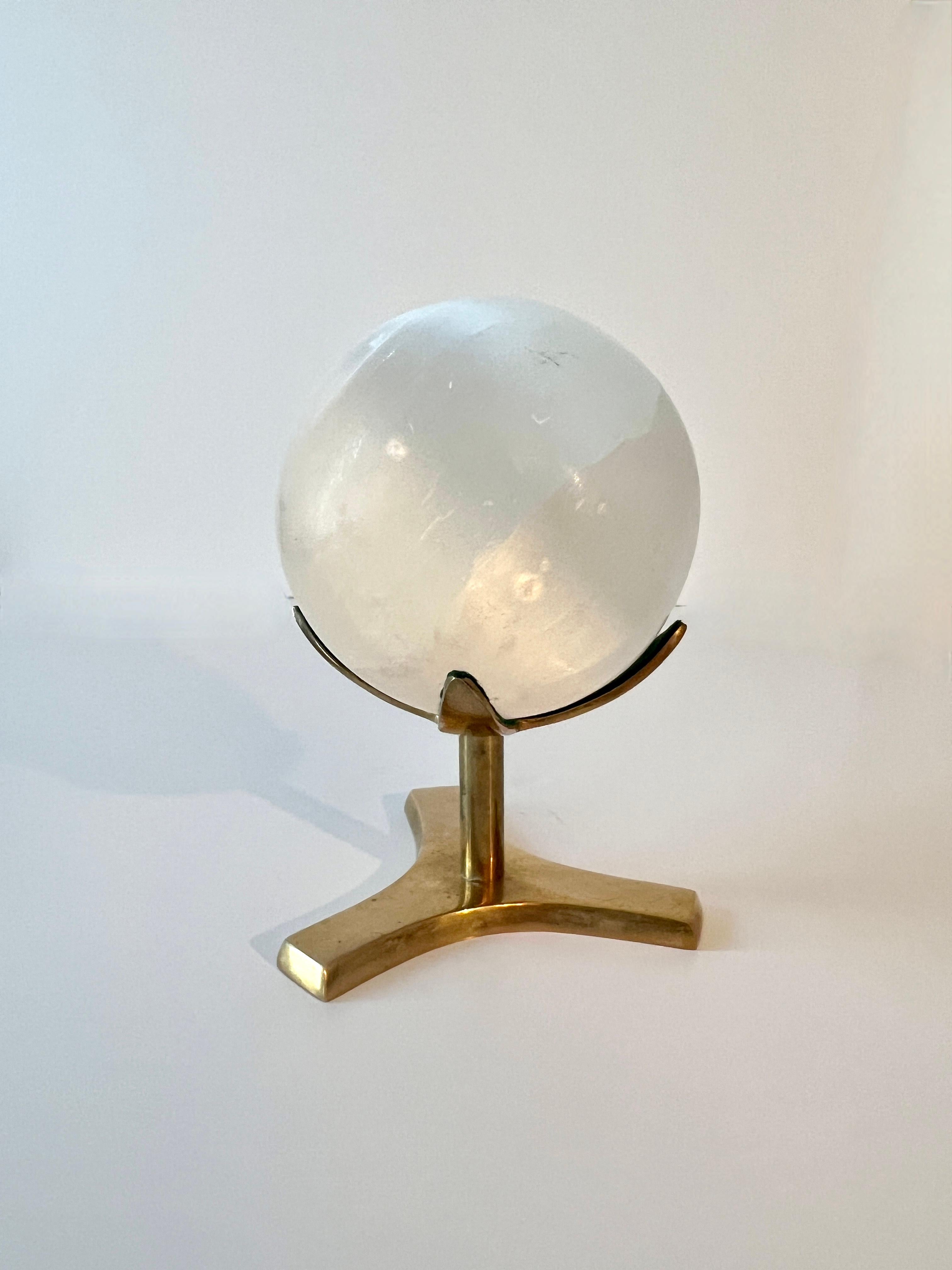 A beautiful ulexite stone sphere, polished and mounted on a brass three prong stand.   The sphere casts great light and is great sitting in a space with a lot of light.  

A compliment to any side table, desk or work station.  these stones bring