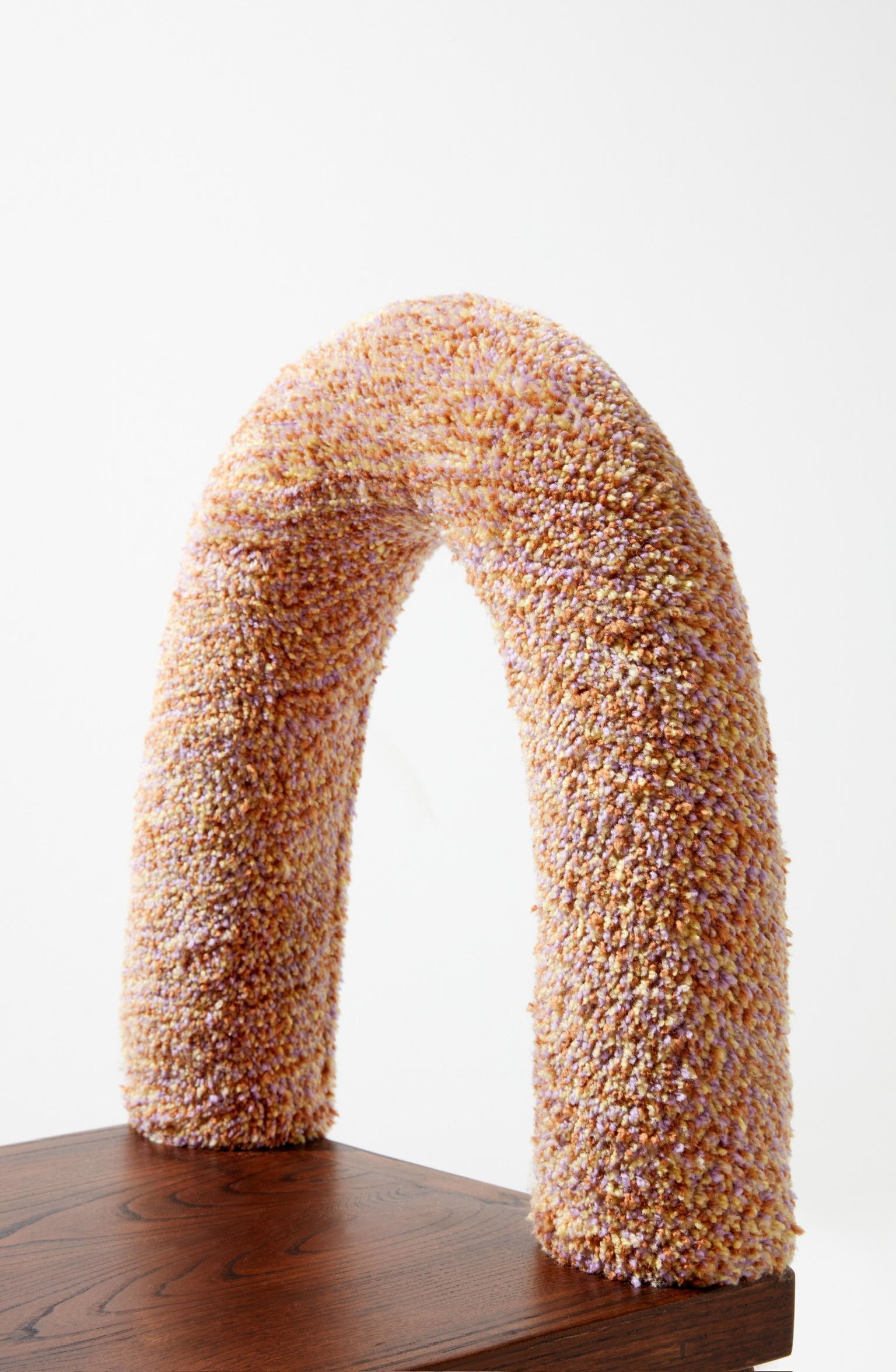 The Honey Chair is crafted using the tufting technique, with a rich blend of brown, purple, and yellow yarns woven together to create a textured and vibrant surface. These carefully selected colors not only strengthen the chair’s connection to the