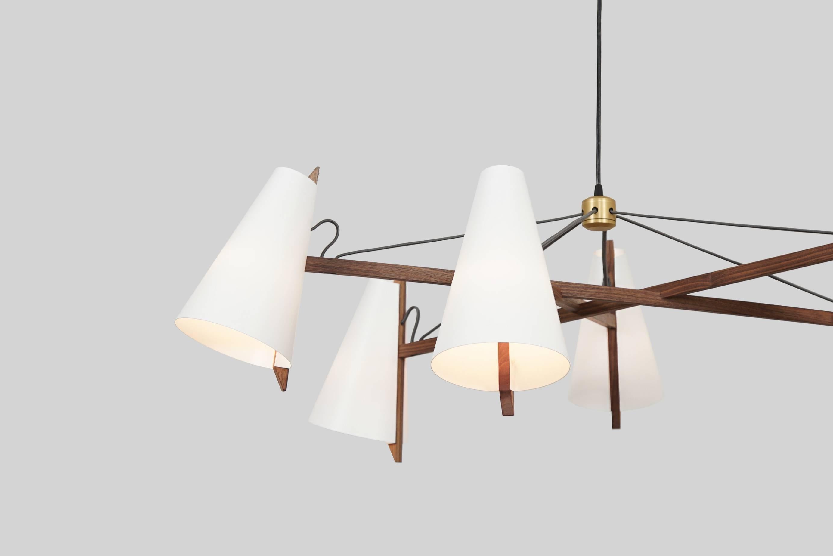 The Hood Family is inspired by wooden sailboats and the work of Aino Aalto. Thin sheets of polyethylene are die cut and bent, joining narrow spines of white oak to create the hooded shade. The complex joinery of the pendant and chandelier results in