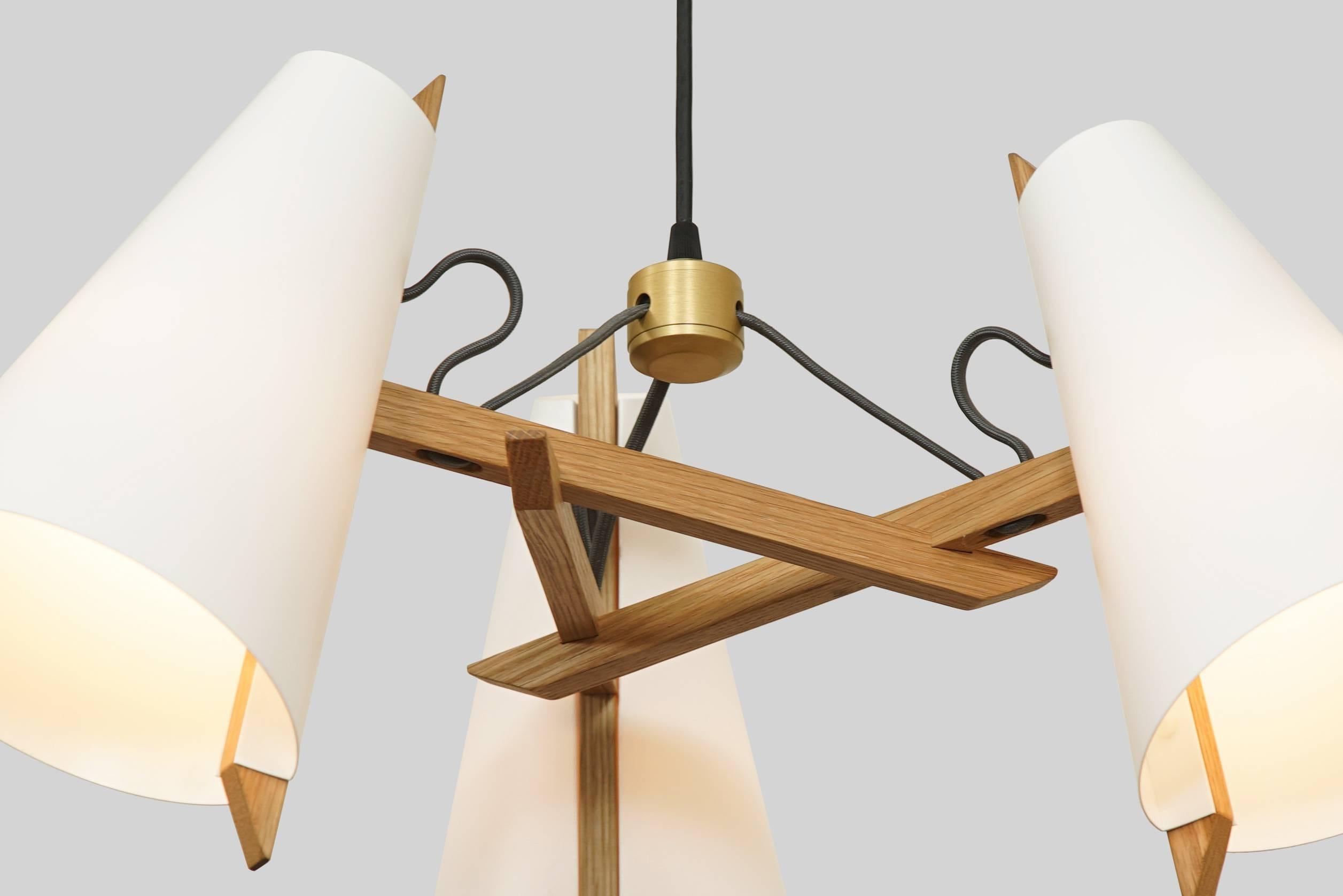 The Hood Family is inspired by wooden sailboats and the work of Aino Aalto. Thin sheets of polyethylene are die cut and bent, joining narrow spines of white oak to create the hooded shade. The complex joinery of the Pendant and Chandelier results in