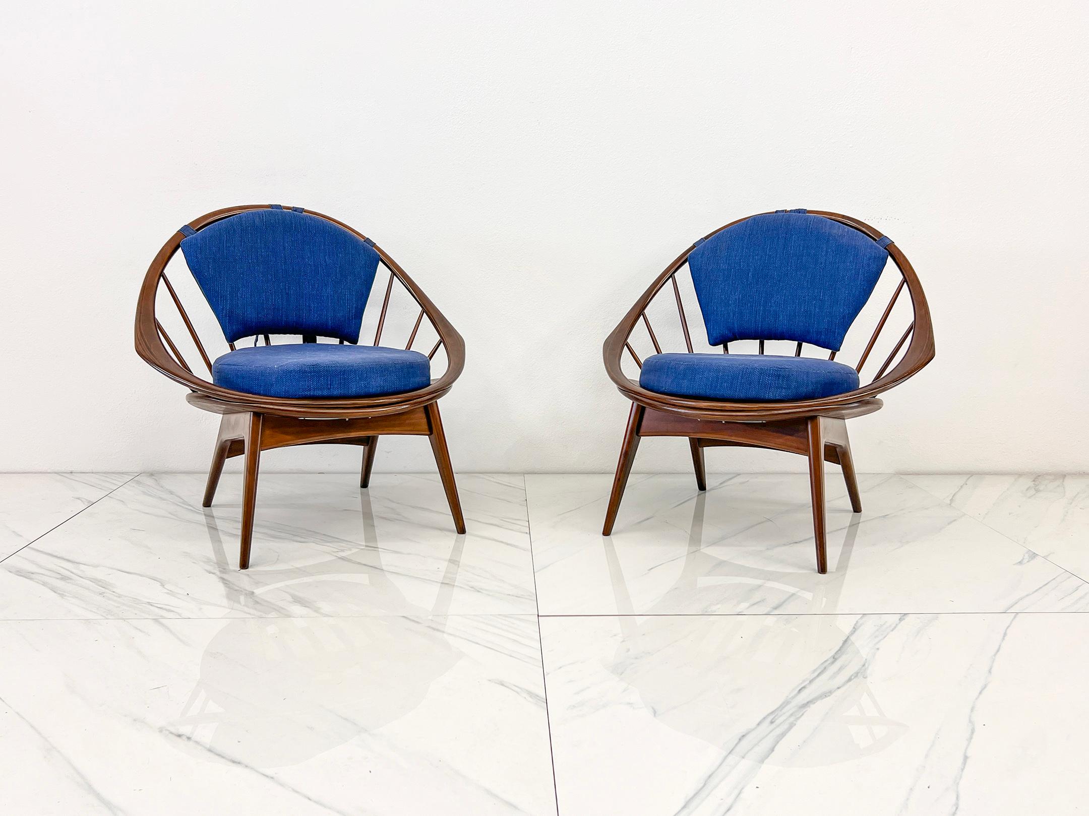 Rara coppia di sedie a cerchio Ib Kofod-Larsen in noce e cobalto, tutte originali.

In questa occasione viene offerta una rara ed eccezionale coppia di iconiche Hoop Chairs di Ib Kofod-Larsen, realizzate in noce massiccio e dotate di cuscini e