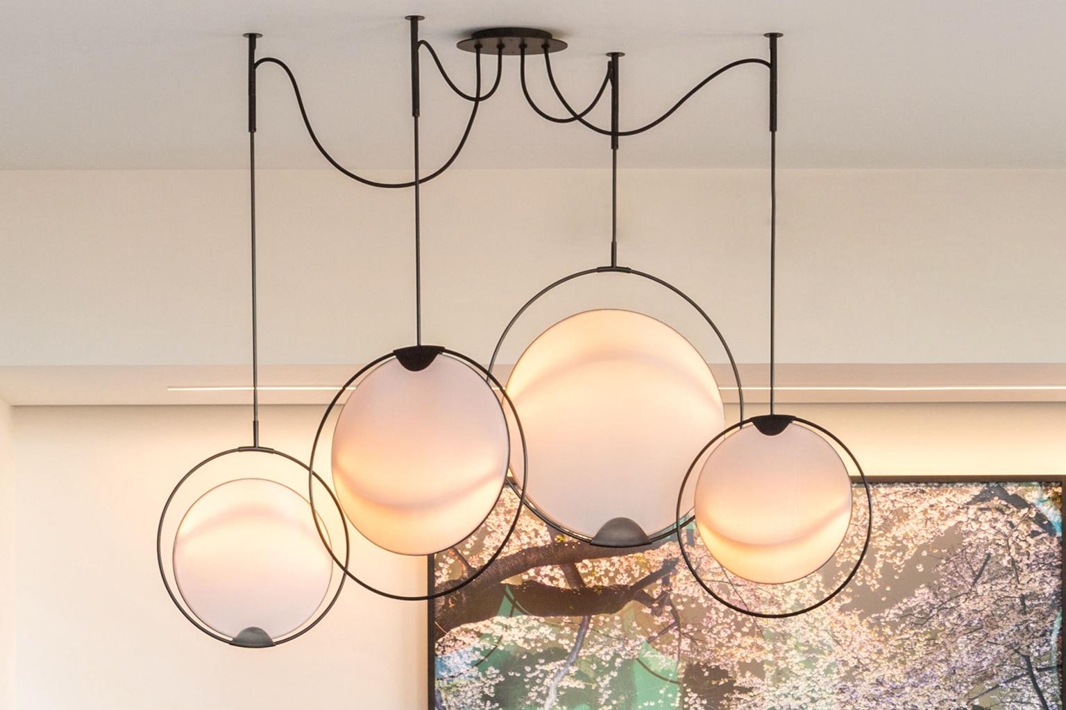 The hoop shade was inspired by the construction and dynamic motion of hoop skirts from the early 1900s. The large brass hoops rotate back and forth, and the shades rotate within those hoops, allowing the user to adjust the light to their needs.
