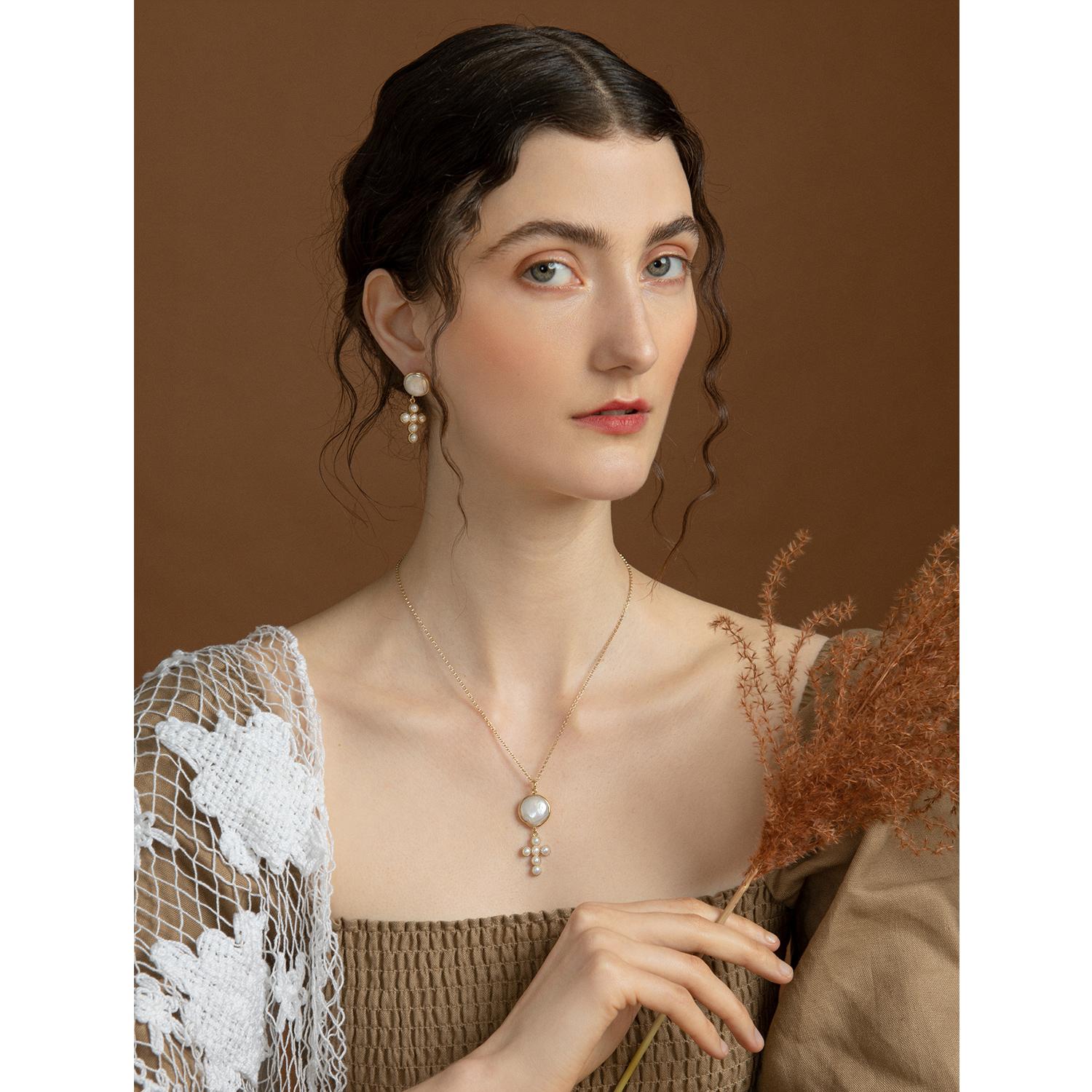 Handmade in Italy from 18-karat gold-plated silver, these pair of earrings from the Hope collection by Vintouch Jewels are balanced by a single one-of-a-kind baroque pearl and a dainty cross pendant enriched by lustrous freshwater pearls. Each pearl