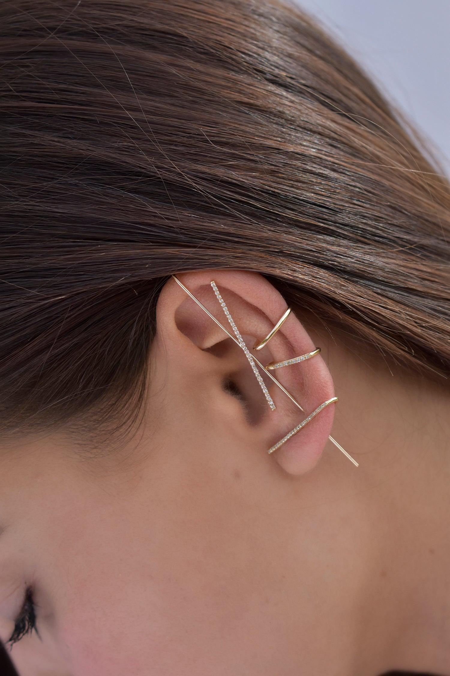 La boucle d'oreille Horizon Needle est constituée d'une délicate tige en or ressemblant à une aiguille, avec une barre transversale ornée de diamants. Ce style crée une illusion saisissante sur votre oreille. Portez-la seule ou en combinaison avec
