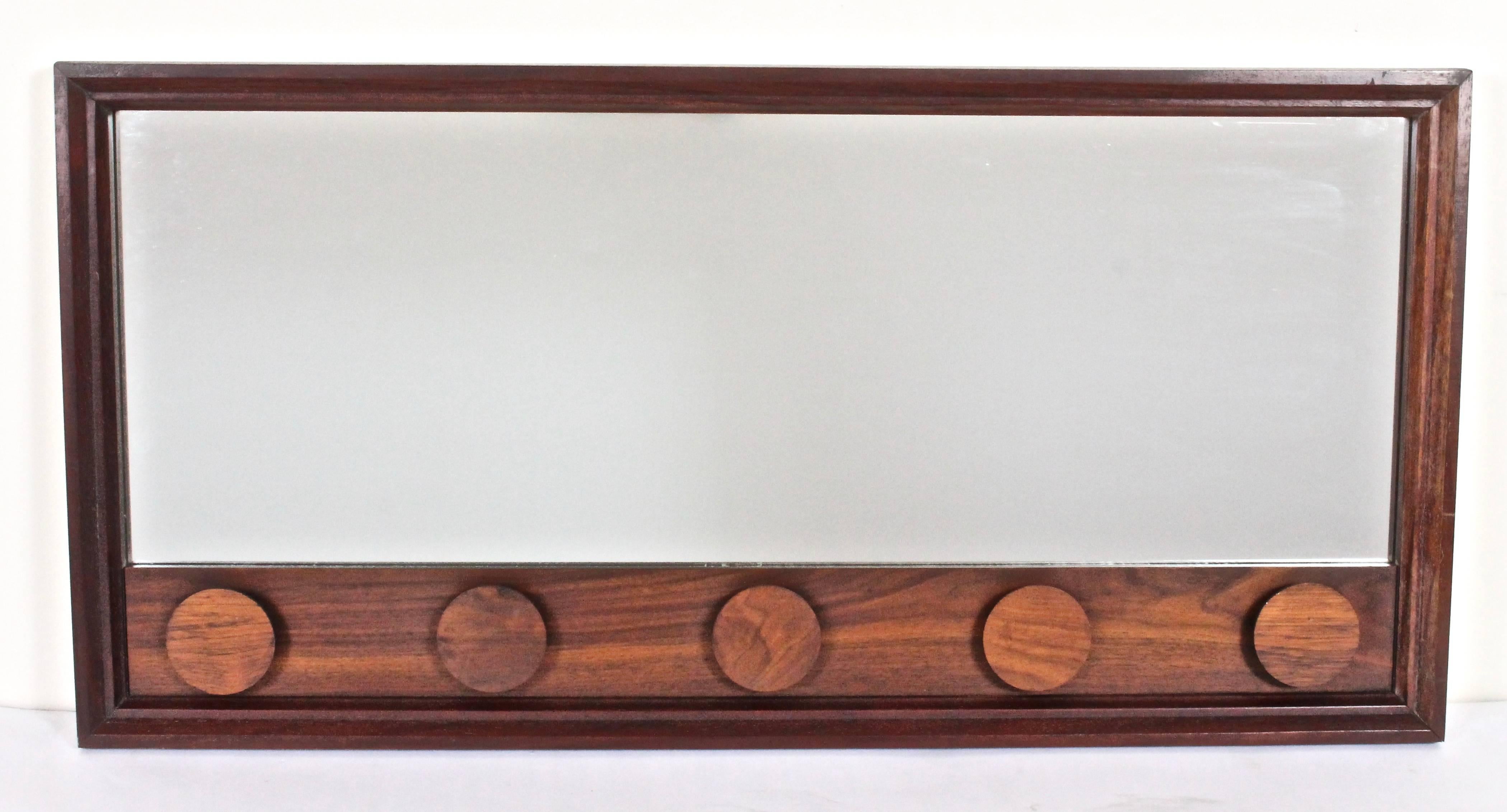 Danish Mid-Century Modern Rosewood Framed Beveled Mirror with round Rosewood disc detail.  Featuring rectangular solid beveled Rosewood frame, beveled mirror with five raised round appliques suitable for hanging objects. Jewelry. Necklaces. Belts.