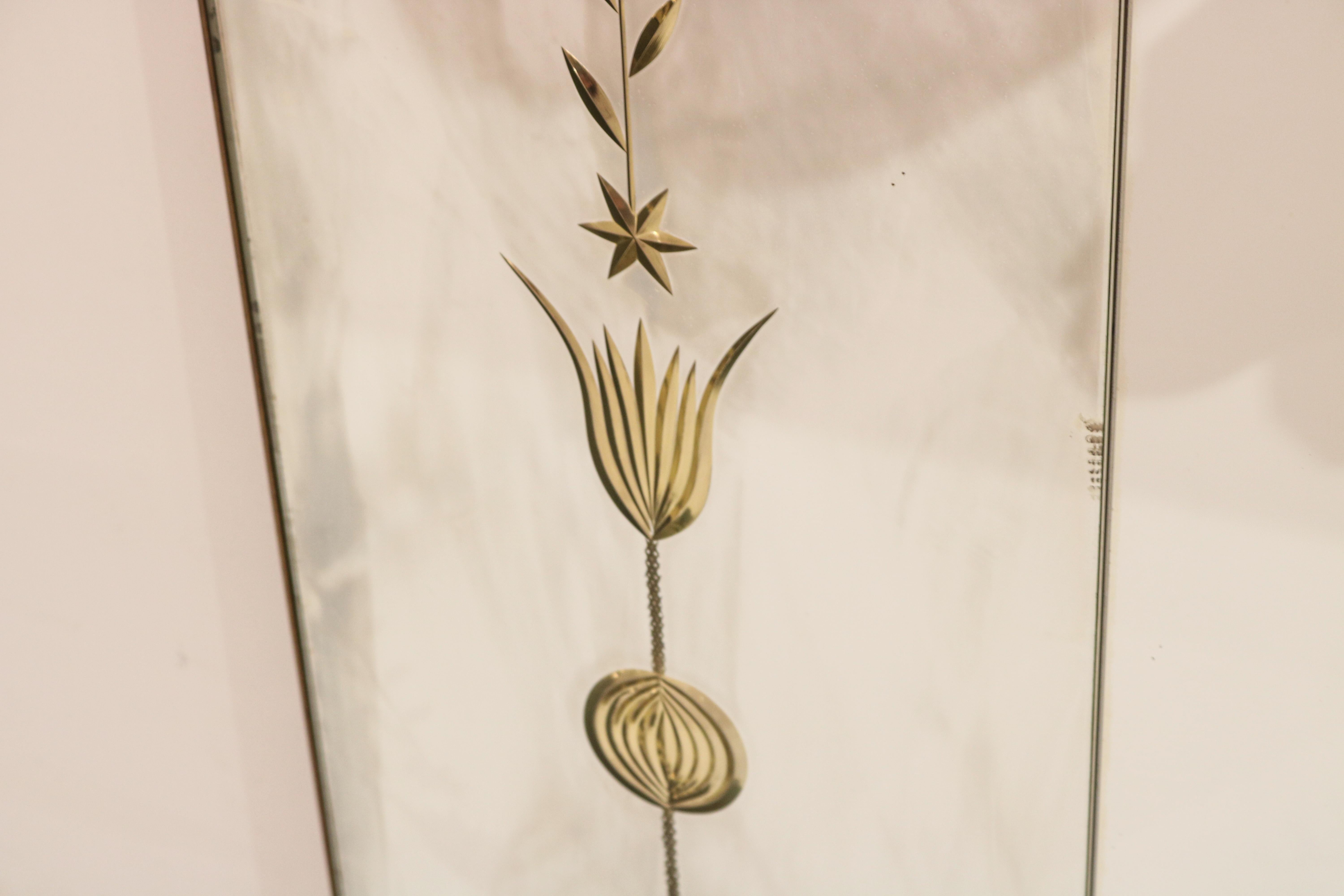 Horizontal Italian Modernist wall mirror. 
Three mirror panels surrounded by a patinated brass border
with floral inset brass details on the panels flanking the cental mirror.