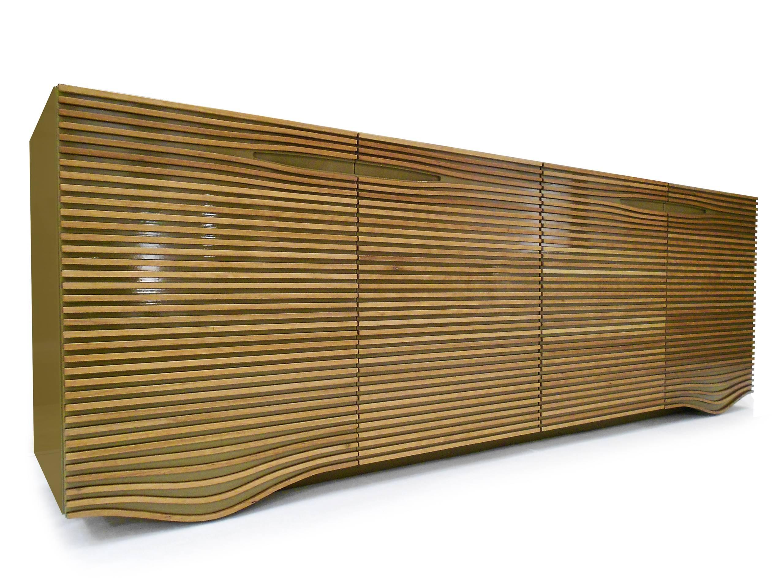 On this sideboard the horizontal lath twists at some sections giving an impression of movement to the doors’ surface, forming the support to the floor and openings for the doors handles. The result outlines a fluid surface which surprises precisely