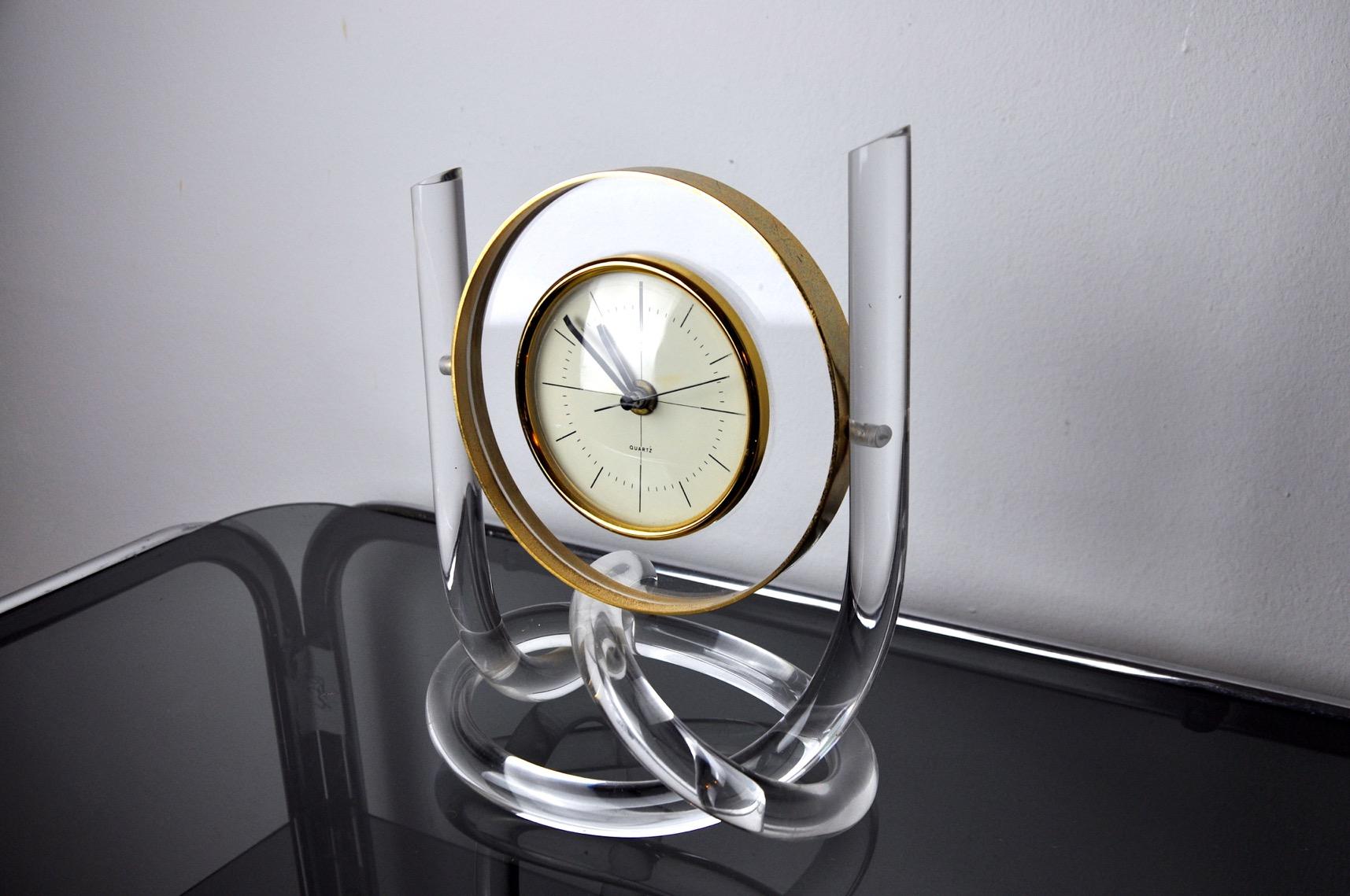 Lucite clock from the 1970s with a golden colored brass support. Hollywood Regency era. Superb design and vintage object to decorate your interior.
 