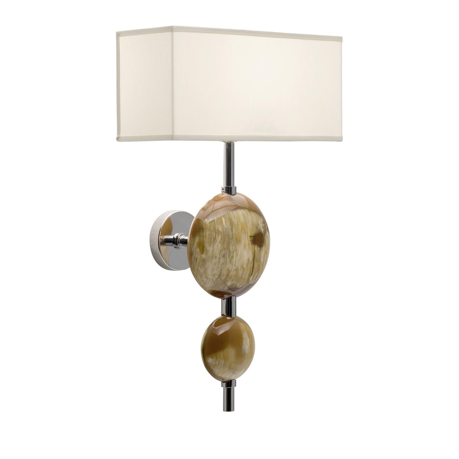 A chic and classic design characterizes this elegant sconce, crafted of stainless steel with a polished finish that will add timeless elegance to any interior. Topped with a rectangular lampshade in ivory shantung, two natural horn disks with soft,